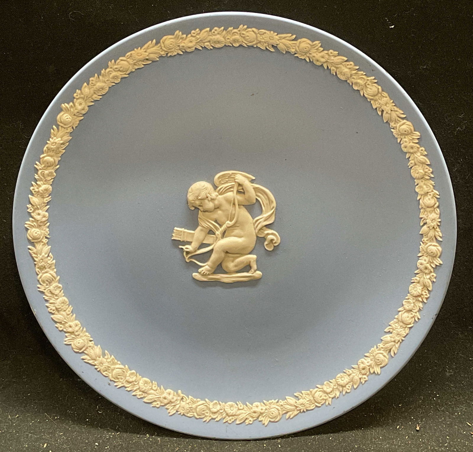Wedgwood Jasperware Cherub Plate, England: Vintage Wedgwood blue Jasperware plate. Bas relief cherub and floral border in white. Signed. Made in England. Measures approx 6.5 inches wide. Some scratching and marks. Wedgwood, Wedgwood plate, Jas