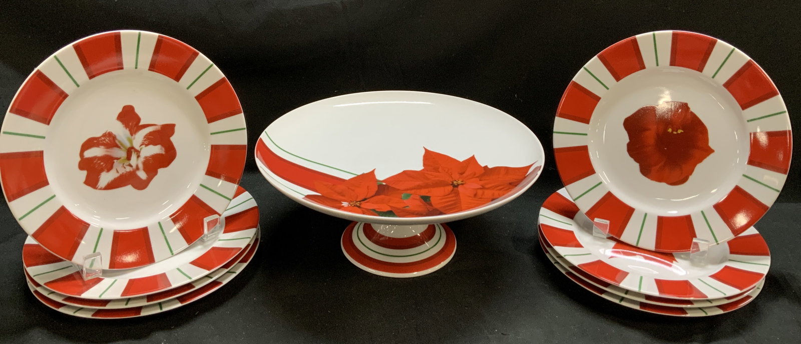 Lot 9 Lord&Taylor Poinsettia Plates & Stand JAPAN: Lot includes, 8 plates & 1 cake stand. Pieces feature a red and white striped rim with green accents and a central floral motif, possibly a poinsettia. Signed & marked on underside. Reads, LORD & TAYL