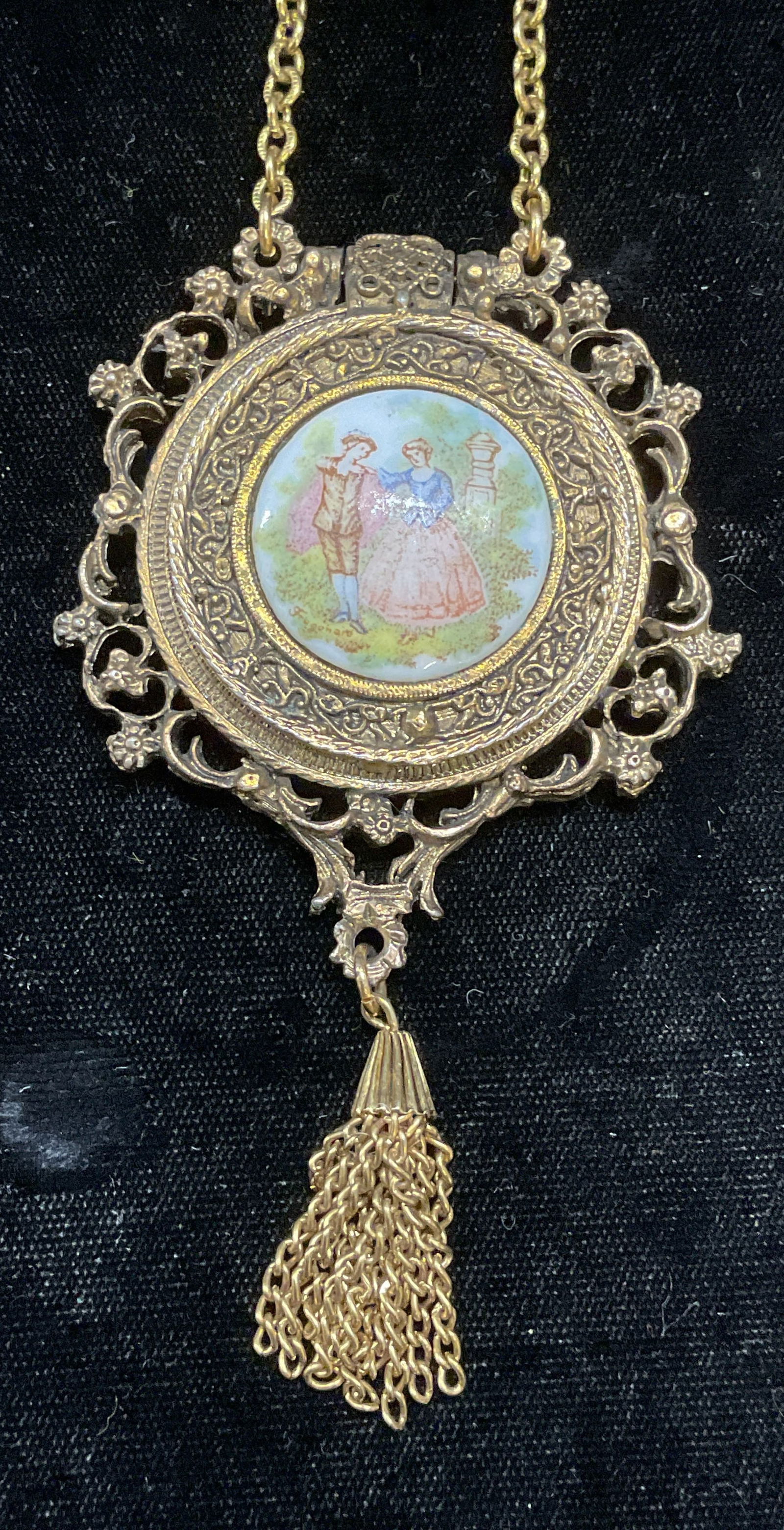 Vtg Gold Tn Hand Painted Locket Pendant Necklace: Vintage gold tone pendant necklace with hand painted porcelain courting couple motif. Locket pendant with space for photograph on interior. Drop length approx 15 inches, pendant approx 4 x 2.25 inches