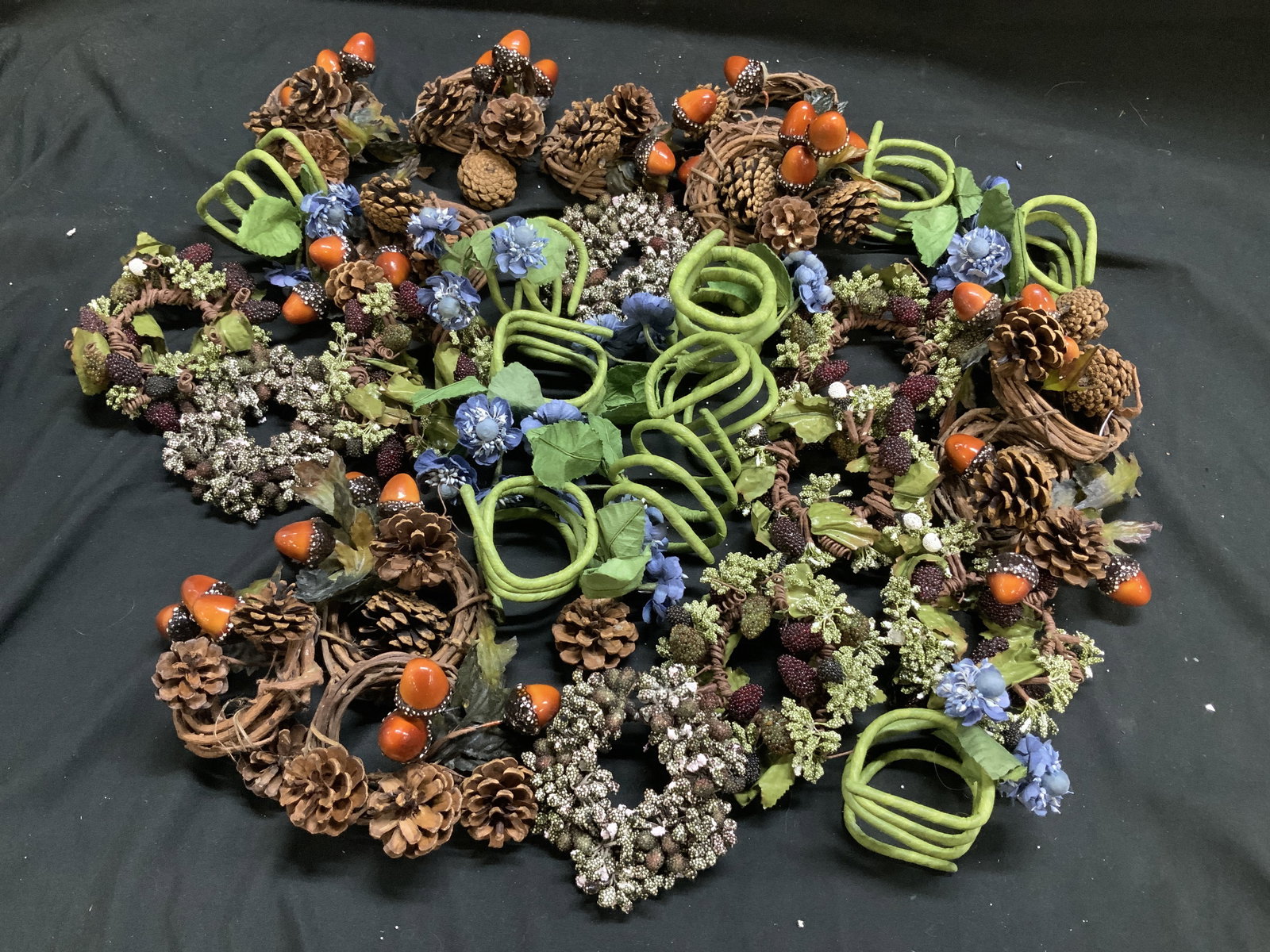 Lot 30 Autumn Botanical Artificial Napkin Rings: Lot includes 30 napkin rings featuring an autumn/fall theme. Napkin rings feature artificial pinecones, acorns, artificial berries, artificial leaves & artificial blue flowers. Surface wear consistent
