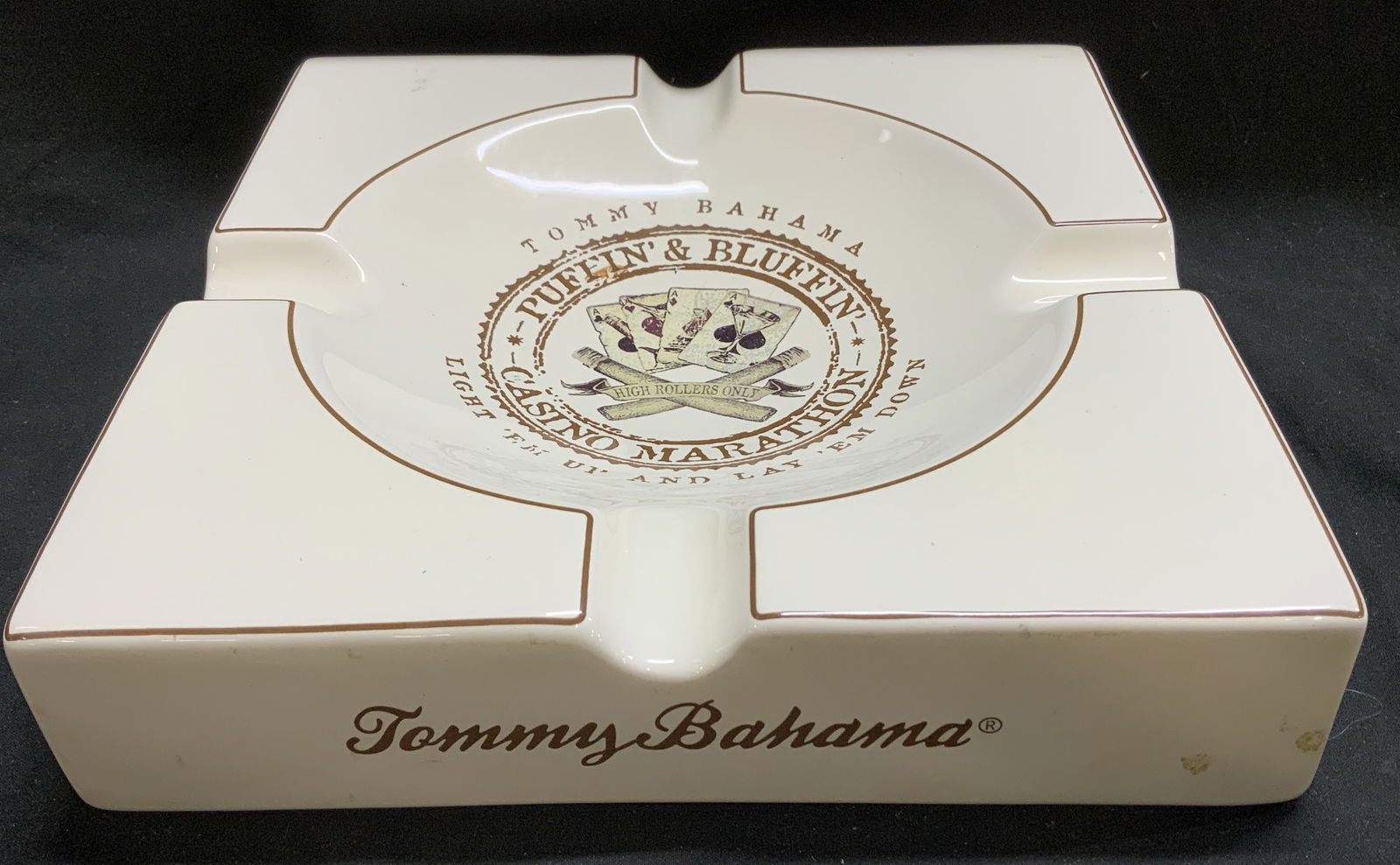 2008 Large Tommy Bahama Puffin & Bluffin Ashtray: Ceramic ashtray features playing cards in the center & lettering that reads, PUFFIN & BLUFFIN. CASINO MARATHON. LIGHT FM UP & LAY ?EM DOWN. Signed & marked on underside. Reads, TOMMY BAHAMA. 2008 TOMM