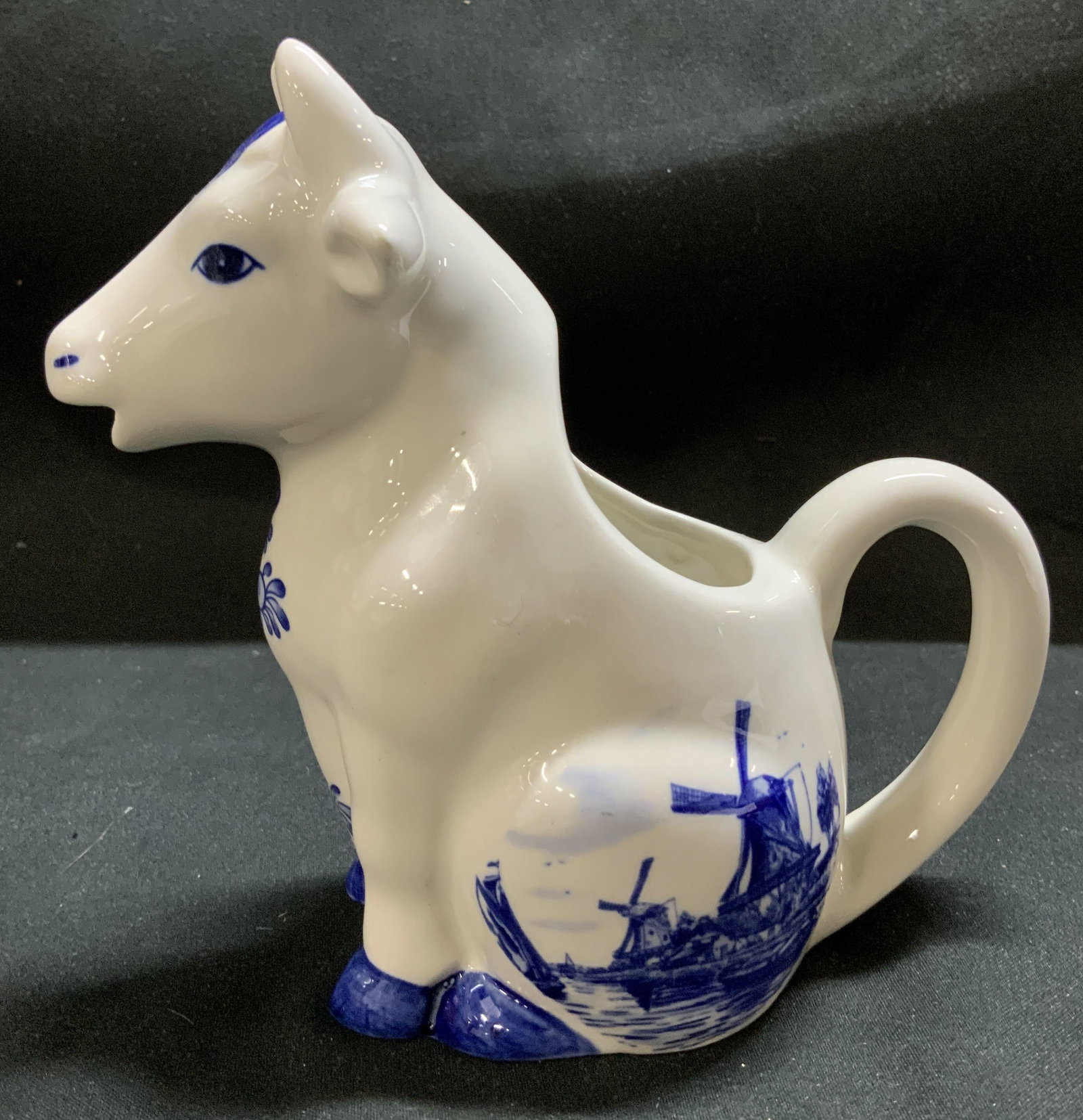 Vntg Delft Blue Seated Cow Creamer HOLLAND: Creamer appears to be made of porcelain material & features a hand-painted delft blue pattern of traditional windmills. Creamer is shaped like a seated cow. Signed & marked on underside. Reads, DELFT 