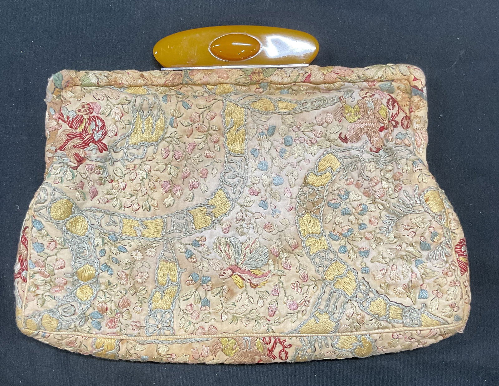 Vintage Reich Embroidered Handbag, Austria: Vintage Reich hand embroidered clutch handbag. Ornate floral pattern in pastel palette. Orange Bakelite clasp. Signed, made in Austria. Material feels like cotton. Measures approx 5.5 x 8.5 inches. We