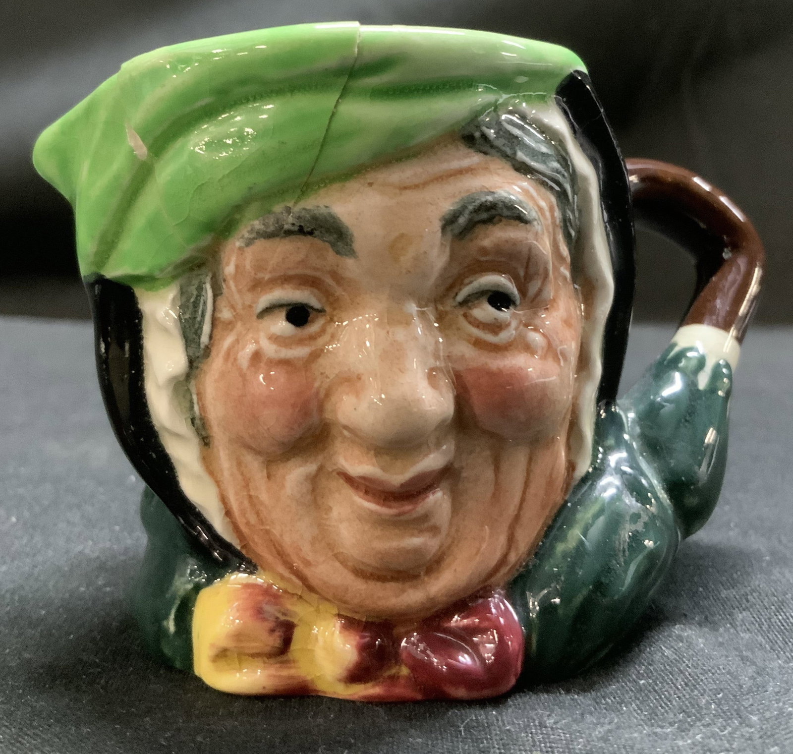 Vntg Royal Doulton Sairey Gamp Toby Jug ENGLAND: Miniature Tuby jug depicts Sairey Gamp with her distinctive green hat & yellow and burgundy bow. Jug reads, Sairey Gamp. Features a glossy finish. Signed & marked on underside. Reads, MADE IN ENGLAND.