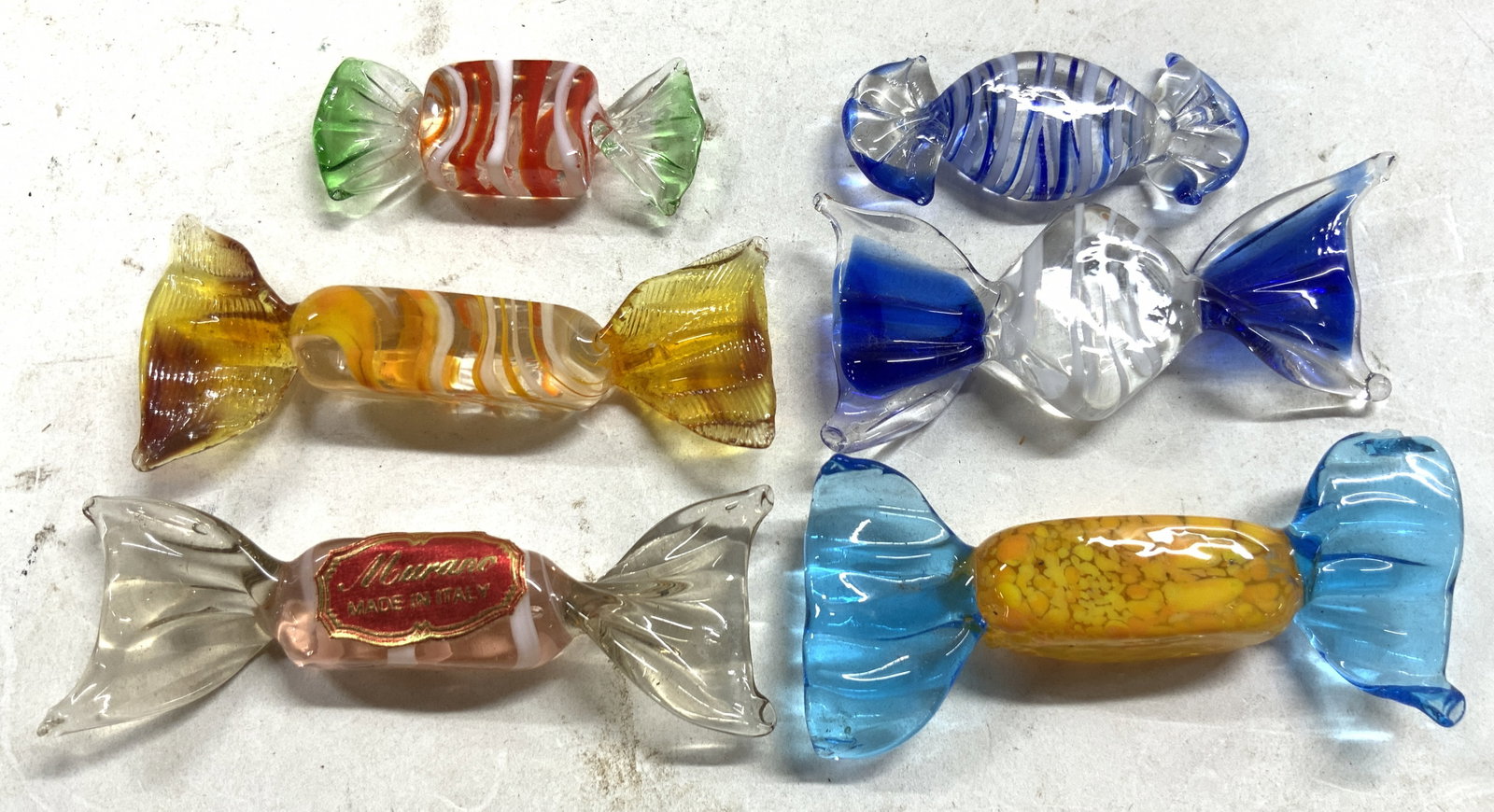 MURANO Italy Hand Crafted Art Gls Candy Figures: Tag on one candy figure reads MURANO MADE IN ITALY. Lot includes 6 Art glass candy figures, each with various toned. Glass candies appear to be hand crafted. Largest measures approximately 3.25 inches