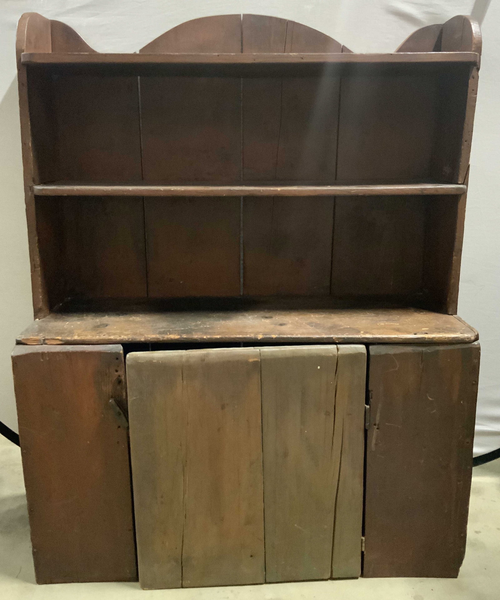 Antique Wooden Cupboard W Shelf & Cabinet 50in: Cupboard is antique. Piece is brown toned and wooden. Cupboard has shelf and cabinet. Top of piece has curved structure. Measures approximately 50 inches tall 40 inches wide 15 inches deep. Cupboard, 