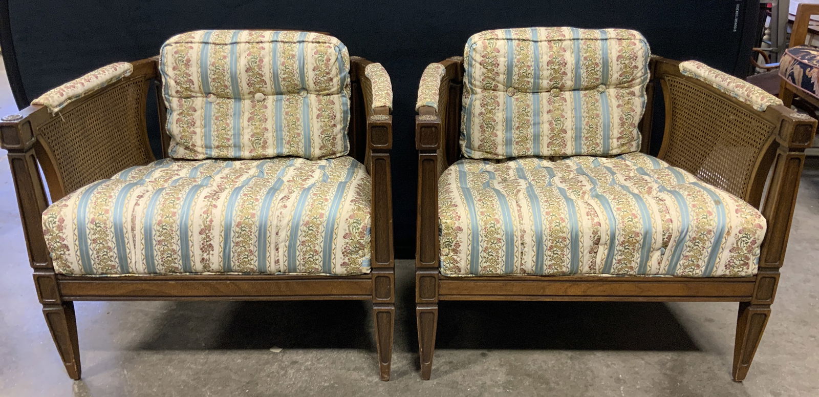 Vntg Caned Wooden Uph Tufted Armchairs: Lot includes 2 chairs. Chairs are vintage and wooden. Each have brown toned frames with caning. Chairs have horseshoe form backrests. Each have multi toned floral motif and stripe detail. Some edges o