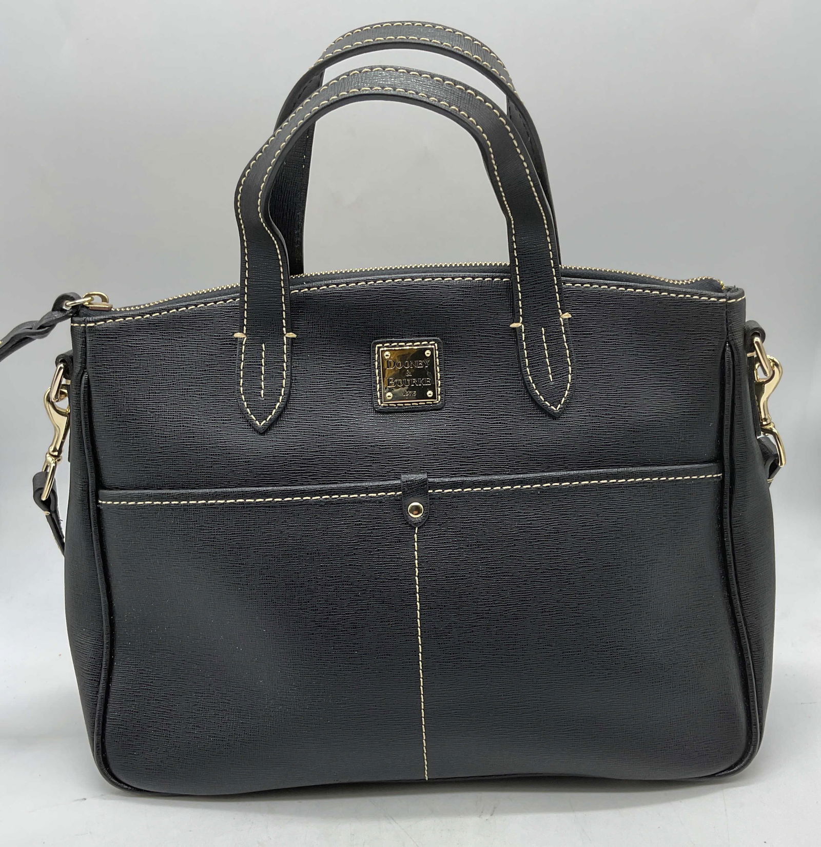 Vintage Dooney & Bourke Black Leather Handbag: Vintage Dooney & Bourke black leather handbag, white contrast stitching, top handles and shoulder strap, outer pockets. Multiple interior pockets, red cloth lining. Signed on leather and hardware. Mea
