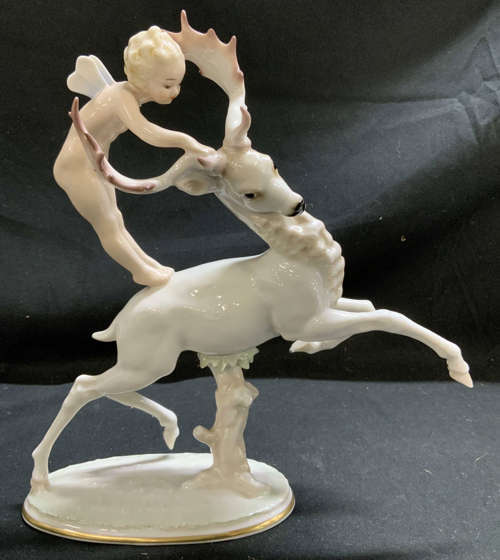 Vtg Hutschenreuther Putti W Deer Porc Fig. GERMANY: Porcelain figurine depicts a putti (a cherubic figure) with a leaping deer. It was designed by Carl Werder, a prominent artist for the Hutschenreuther Art Department. Figurine features gold accents & 