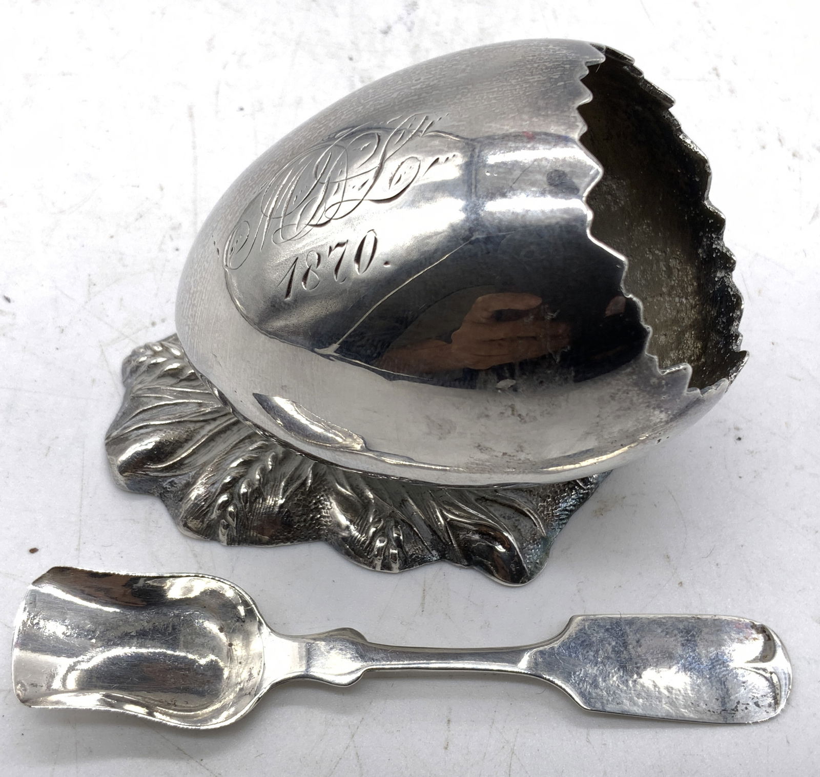 BJ MAYO 887 Atq Quad Pl Crckd Egg Slt Cellar & Spn: Underside reads BJ MAYO 887 QUADRUPLE PLATE BROAD ST NEWARK NJ. Salt cellar is monogrammed (appears to reads MSL 1870). Piece has cracked egg form with leaf base. Lot includes salt cellar and shovel f