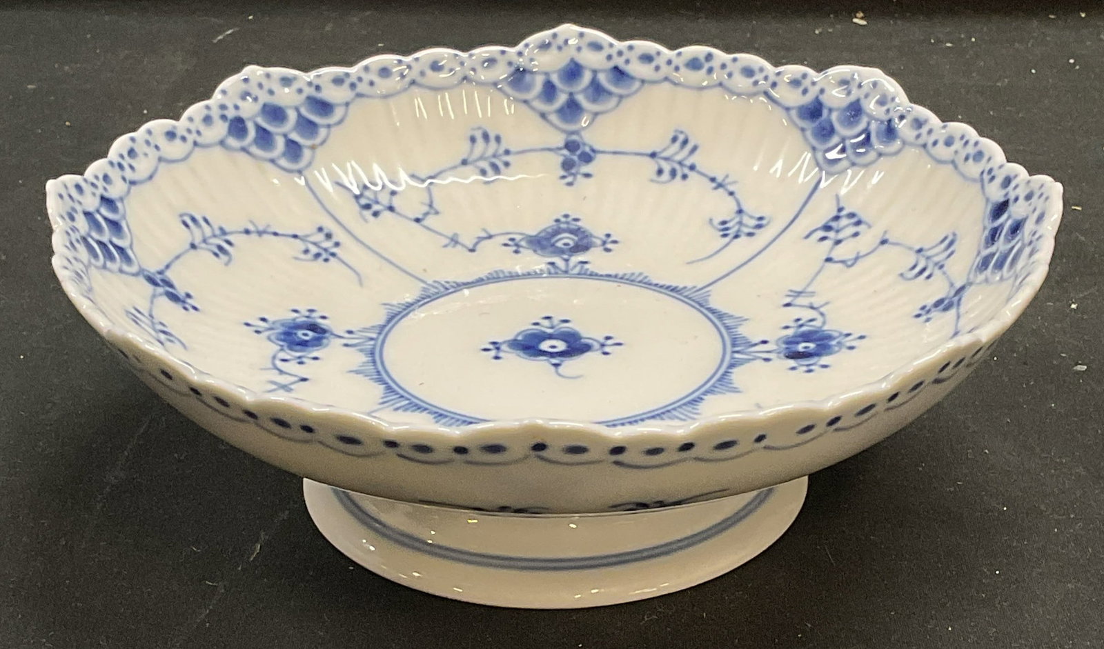 Royal Copenhagen Porcelain Pedestal Bowl: Royal Copenhagen porcelain pedestal bowl. Blue lace pattern. Signed. Made in Denmark. Round bowl with scalloped rim. Hand painted decoration. Measures approx 6.75 x 2.25 inches. Some wear consistent w