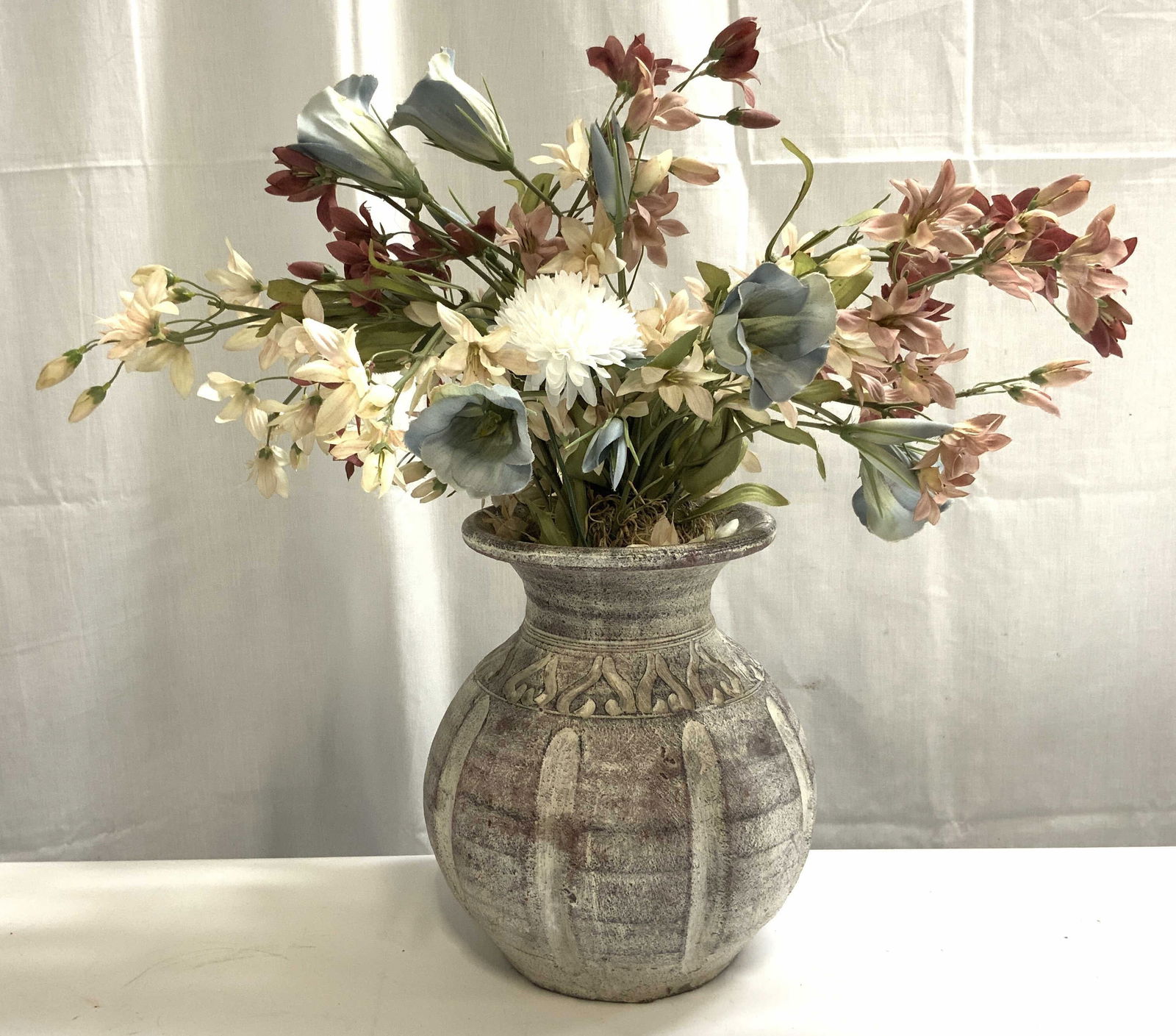 Ceramic Vase W Faux Floral Arrangement: Vase is ceramic. Piece has relief detail to exterior. Inside of vase has multi toned floral arrangement. Vase without floral arrangement measures approximately 8.5 inches tall 7 inches wide. Vase, ves