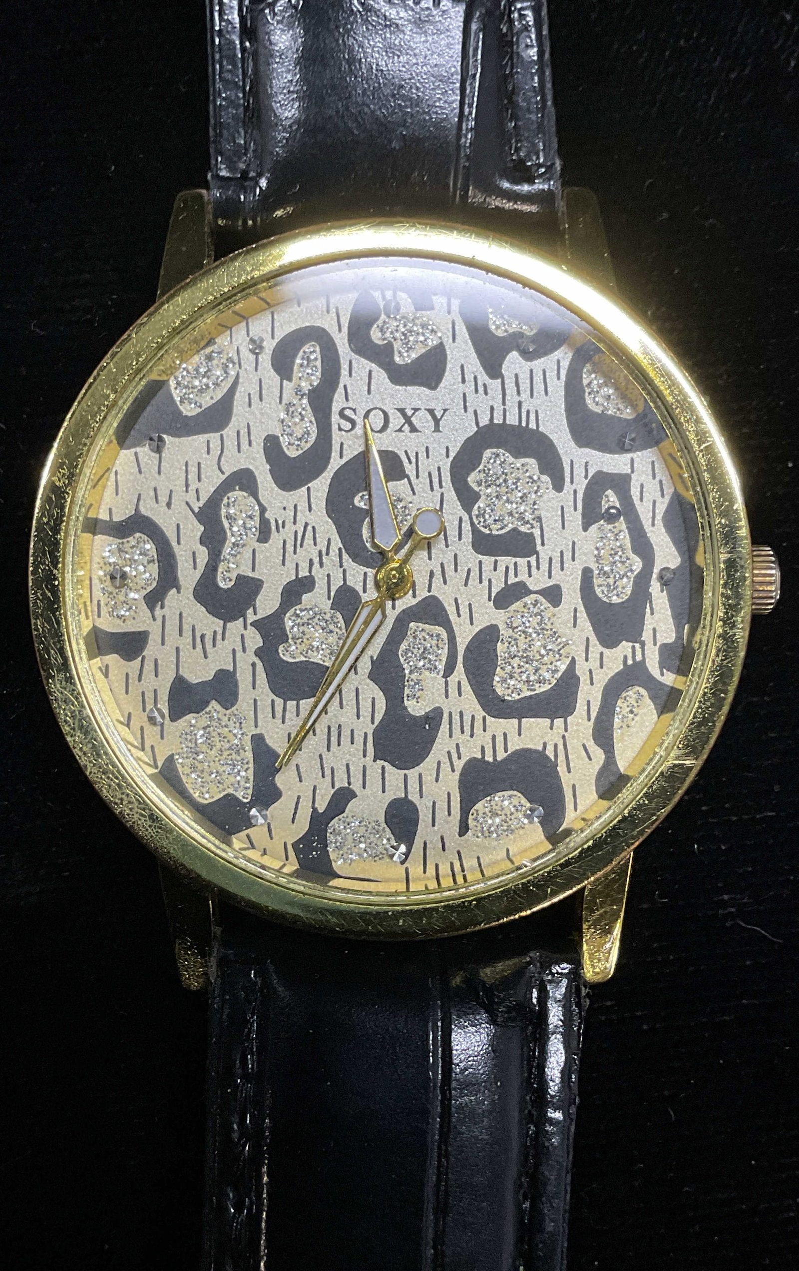 Soxy Gold Tone Cheetah Print Black Strap Watch: Soxy signed gold tone iridescent cheetah print watch with black faux leather strap. Measures approx 9 inches long. Not tested. Some wear including scratching. Jewelry, estate jewelry, costume jewelry,