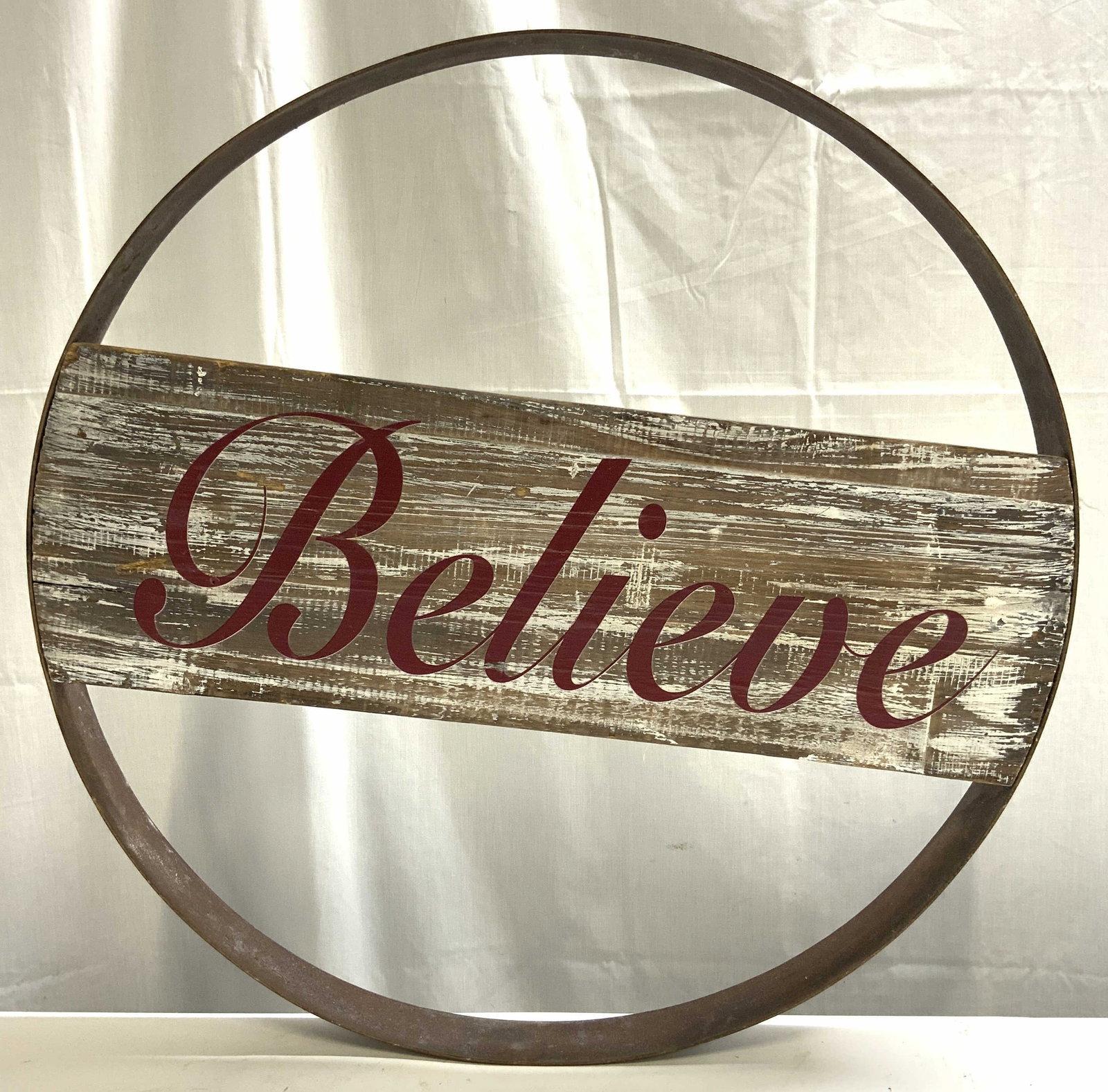 Rustic Circular Believe Christmas Sign: Christmas sign reads BELIEVE. Piece has circular form iron structure. Center has wooden area with red toned script lettering. Piece measures approximately 24 inches diameter. Sign, Christmas sign, bel