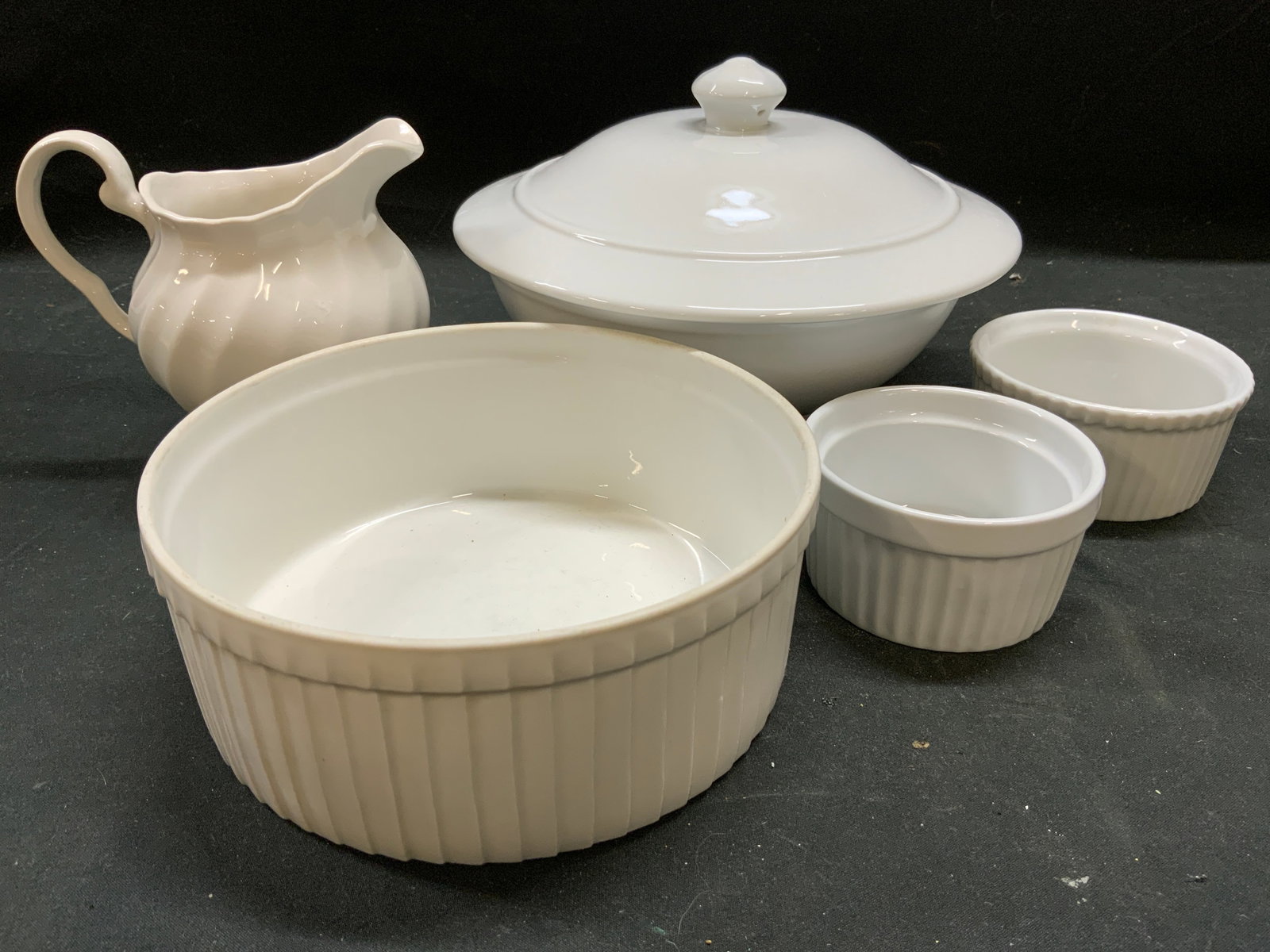 Lot 5 Porcelain Vessels & Ramekins APILCO & More: Lot includes 1 large Ramekin trademarked PILLIVUYT FRANCE, 2 smaller ramekins marked HIC & APILCO, 1 Scalloped creamer inscribed Made IN ENGLAND & 1 serving bowl with lid trademarked IDG, Measures app