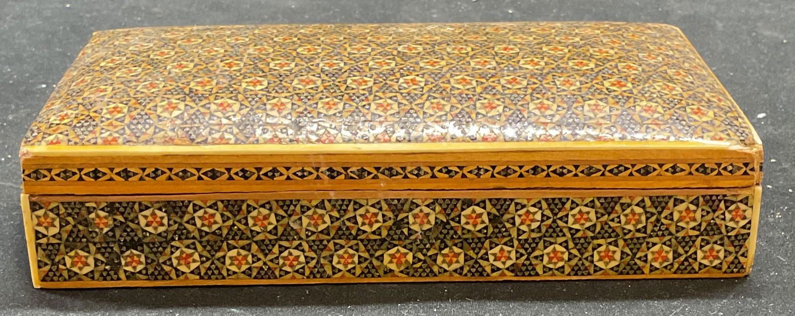 Vtg Persian Khatam Inlaid Marquetry Jewelry Box: Vintage handmade Persian Khatam jewelry trinket box. Inlaid marquetry covered exterior with ornate floral design. Wood and bone. Measures approx 6.5 x 3.5 x 1.5 inches. Side panel on lid needs replace