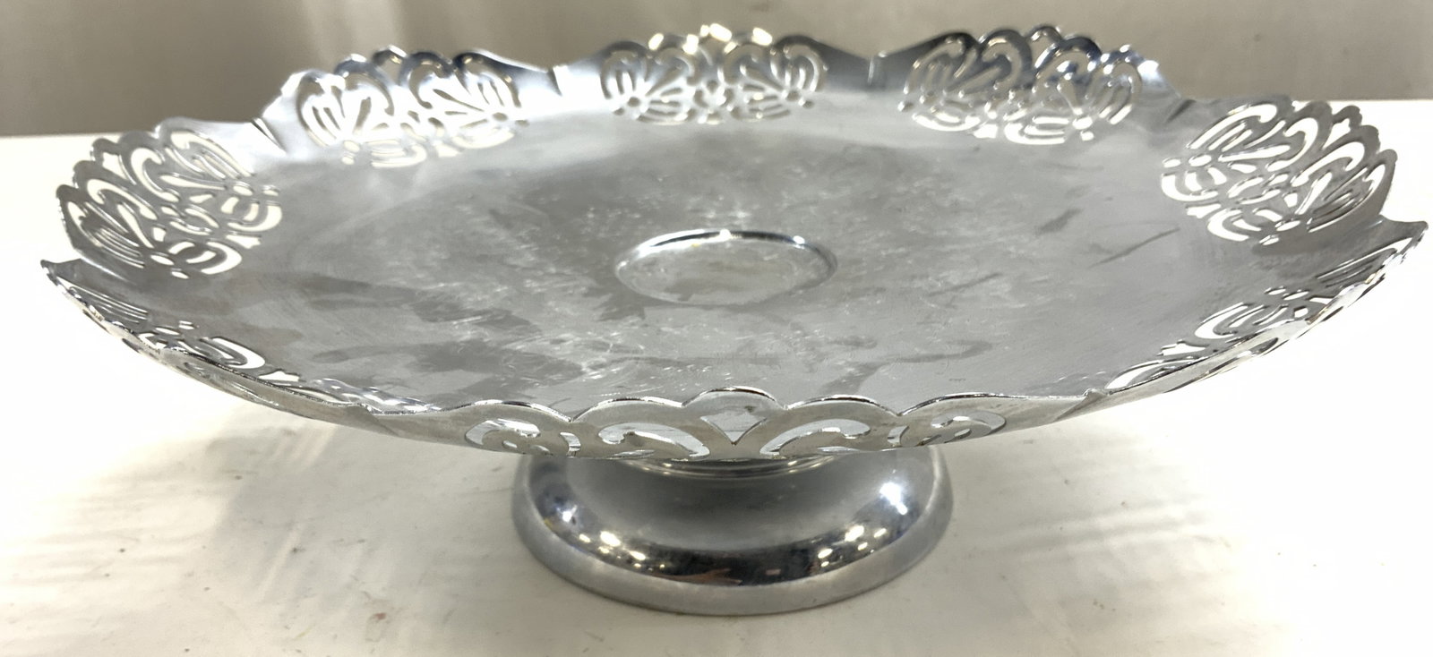 CROMWELL CHROMIUM SILVER MFG CORP Ped Tray: Underside is inscribed CROMWELL CHROMIUM SILVER MFG CORP. Tray is silver toned with pierced detail at edges. Tray is pedestaled. Piece has ornate etched relief detail in center. Piece appears to be vi