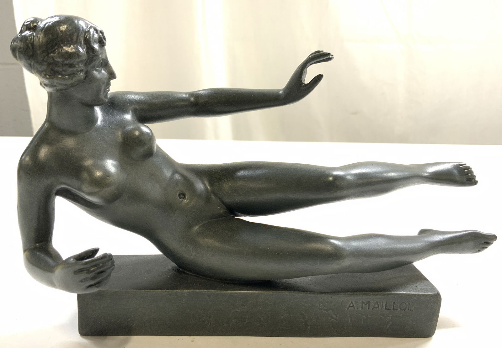 After Aristide Maillol LAir Female Nude Figure: Underside reads ARISTIDA MAILLOL LAIR MOUSEION 3D PARASTONE THE NETHERLANDS. Piece is dark slate toned composite. Statuette depicts a reclining female nude figure. Piece measures approximately 8 inche
