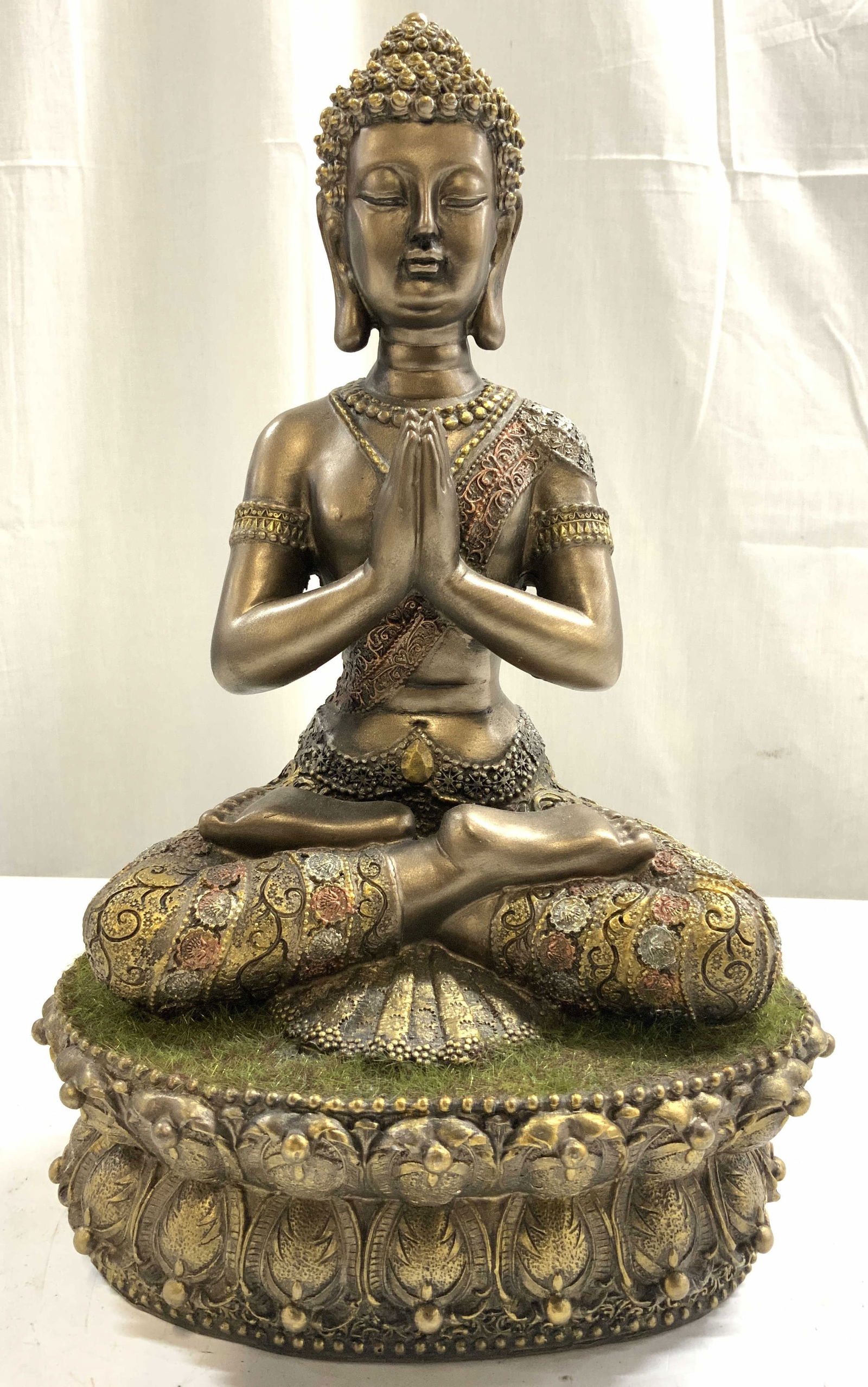 Resin Meditating Buddha W Metallic Finish: Buddha figure is resin. Piece depicts Buddha figure is a meditative position. Figure has a gold toned metallic finish. Base has faux grass detail. Buddha clothing is intricately detailed. Piece measur