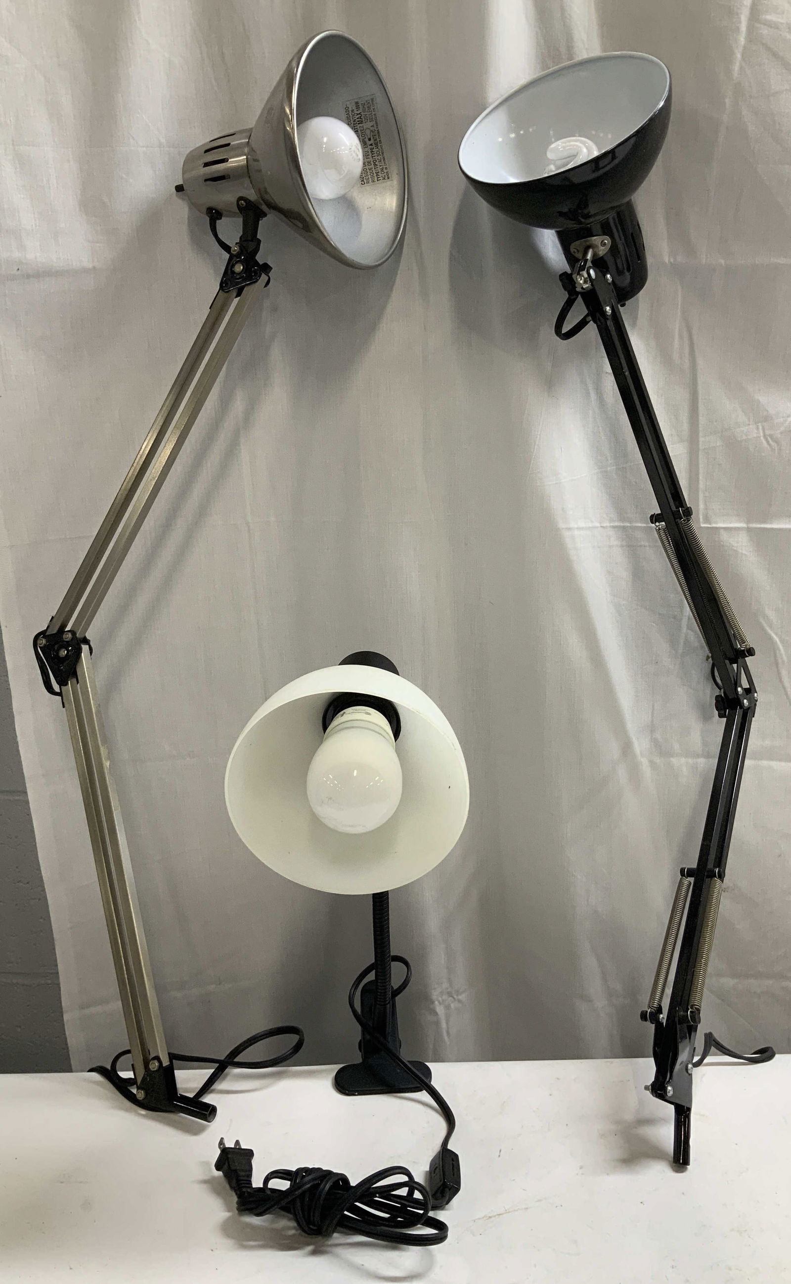 Lot 3 MCM Adjustable Desk Lamps STUDIODESIGNS+: Lot includes, 3 adjustable arm desk lamps. One lamp features a clamped base. Lamps are brushed metal & are black/silver toned. 2 lamps appear to be missing their base to hold them in place. Lamps feat