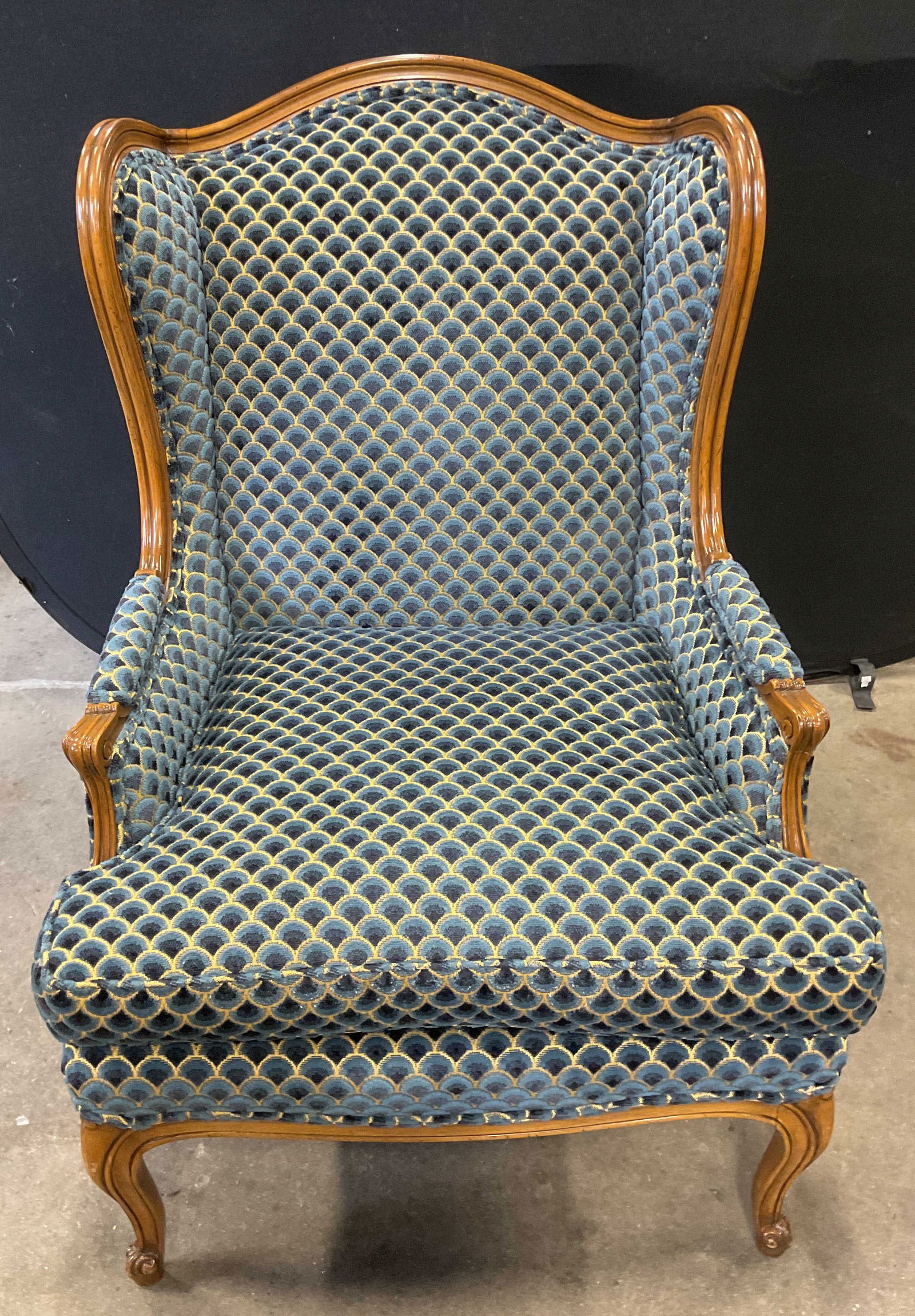 Vintage Blue Velvet Upholstered Armchair: Vintage blue patterned velvet upholstered armchair. Curved back with wood frame and legs. Measures approx 28 inches wide, 21 inches deep, 41 inches tall. Includes upholstery swatch. Some wear to uphol