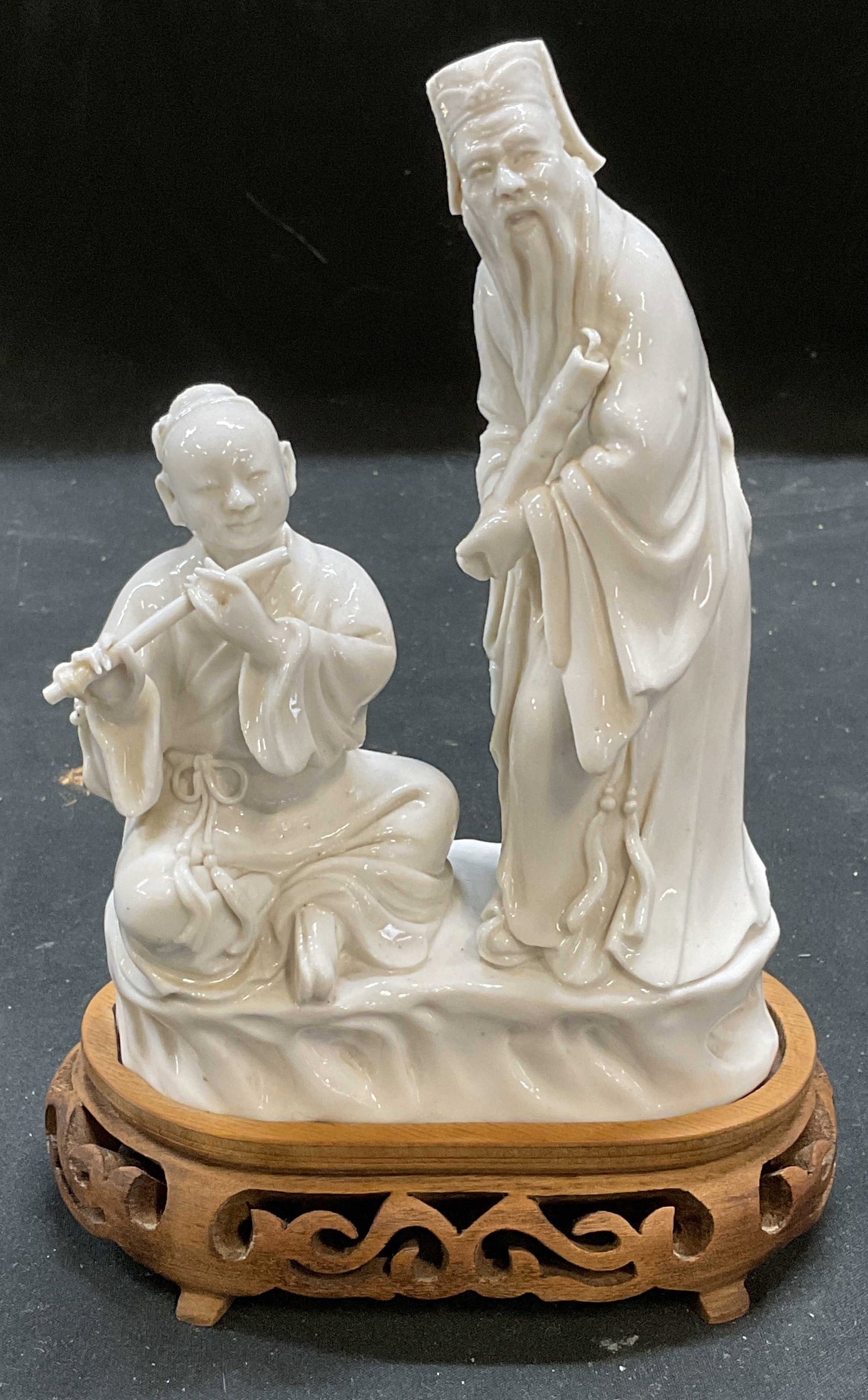 Vtg Blanc de Chine Musician Man Figurine: Vintage Chinese Blanc de chine porcelain figurine affixed to wood stand. Two male figures, flute playing and elder man. Measures approx 5 x 2.5 x 7.25 inches. Some wear consistent with exposure. Blanc