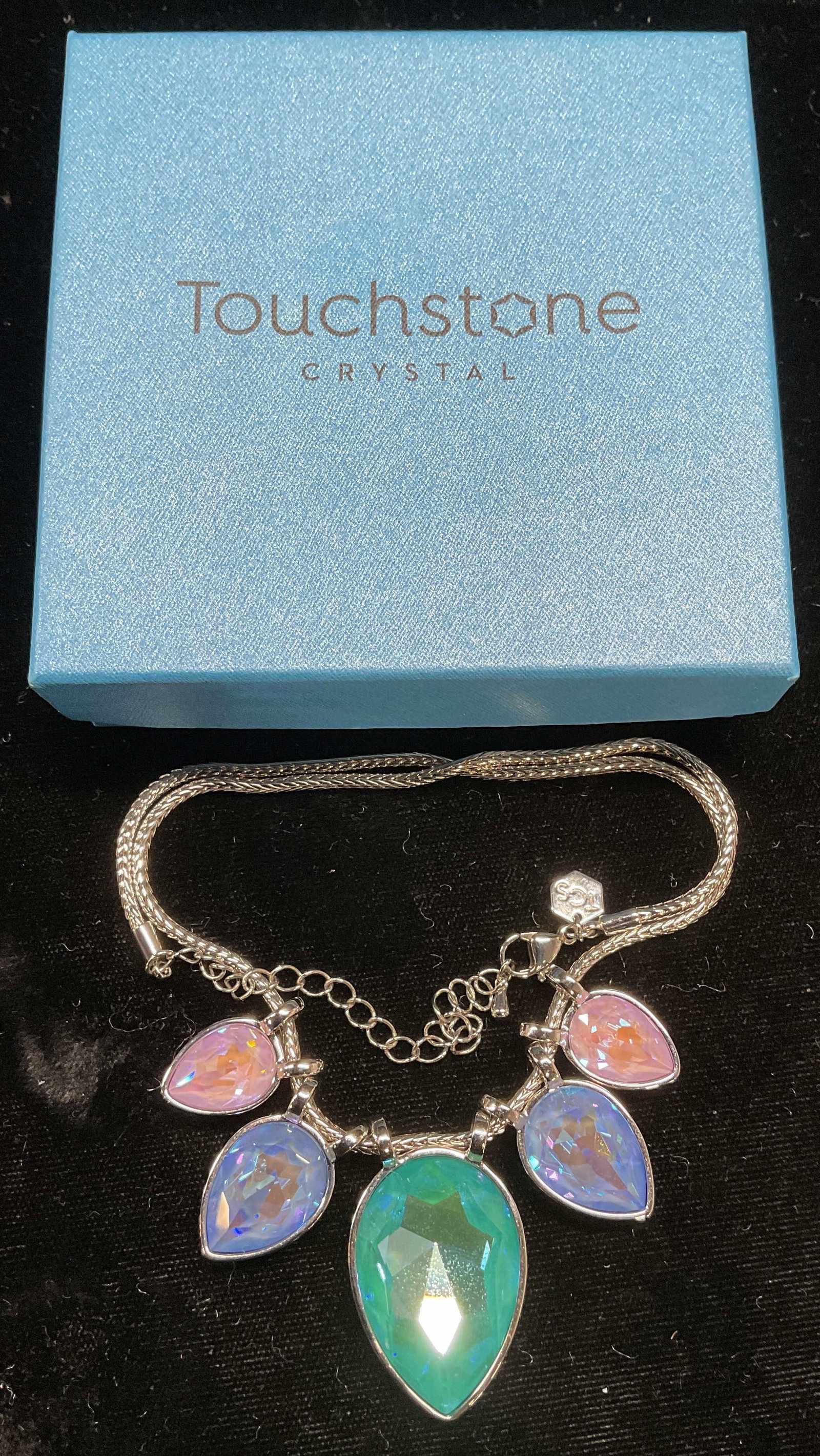 Swarovski Touchstone Crystal Pendant Necklace NIB: Touchstone by Swarovski silver tone pendant necklace. Green, blue, and pink teardrop shaped crystal pendants. Signed. Drop length approx 8.75 inches. New in box. Some wear including scratching observe