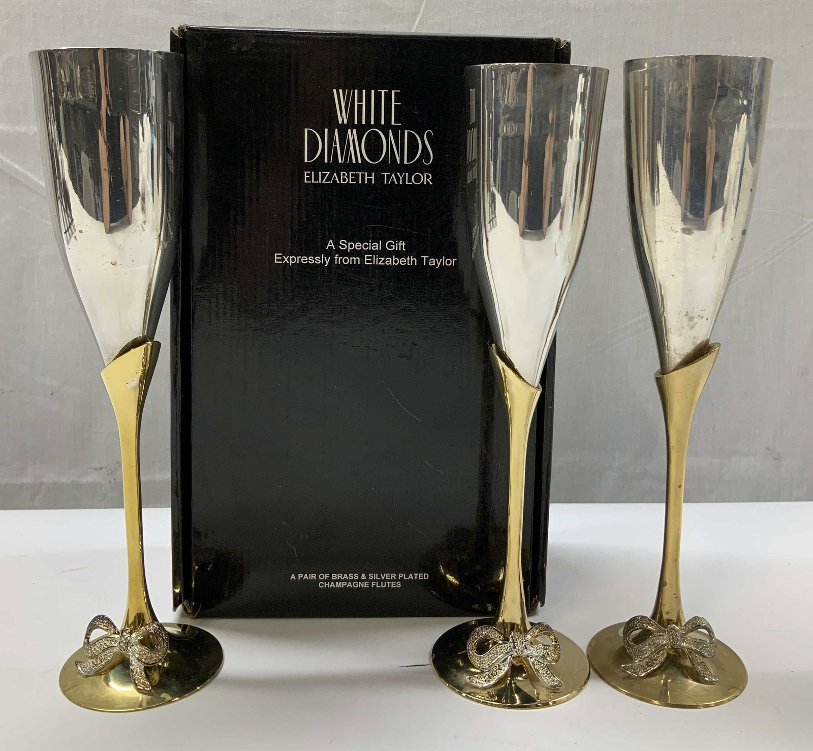 White Diamonds 3 Brass & Slvr Plted Flutes W Box: White Diamonds 3 Brass & Slvr Plted Flutes W Bx Box reads, White Diamonds. Elizabeth Taylor. A special gift Expressly from Elizabeth Taylor. Lot includes, 3 brass & silver plated champagne flutes. The