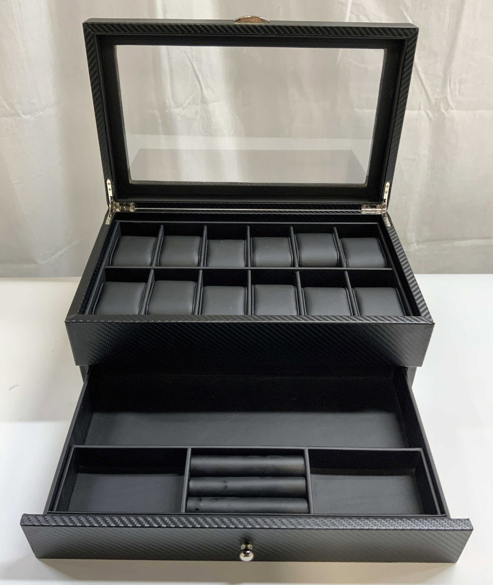 12 Compartment Windowed Watch Box W Drawer: Watch box is black toned, appears to be leatherette with woven style detail. Watch box has windowed lid, 12 compartments & drawer at base. Piece measures approximately 14.25 inches long 8.75 inches de