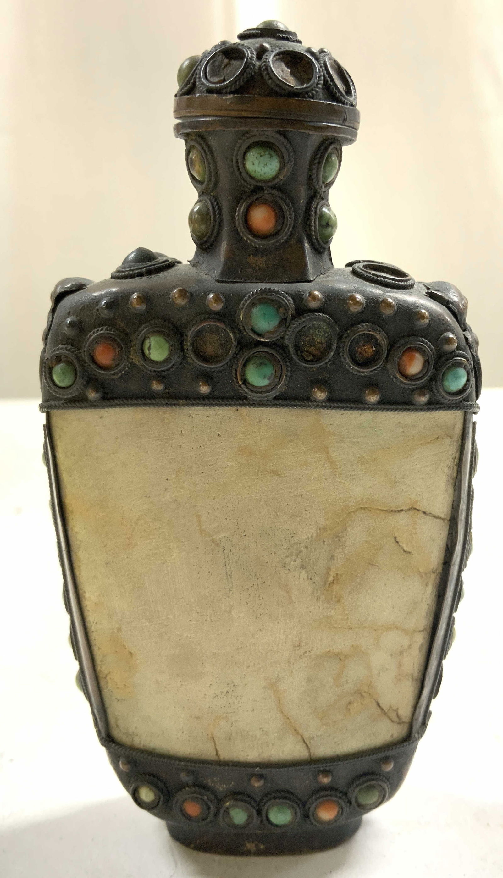 Vintage Tibetan Style Snuff Bottle: Snuff bottle is vintage. Appears to be Tibetan. Exterior has copper lined areas. Includes stopper with attached metal piece. Appears to be crafted with bone and multi toned stones. Side of piece have