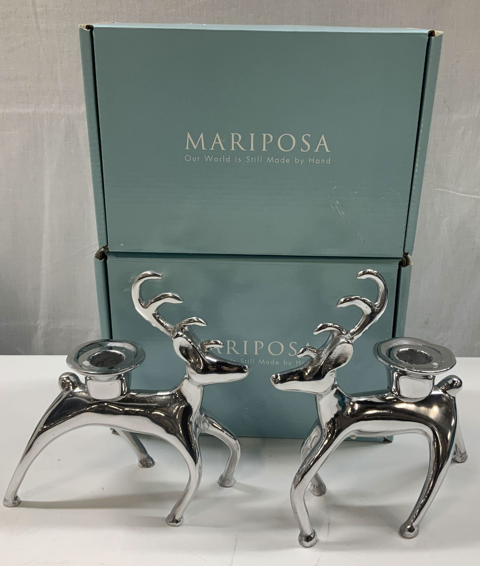 Lot 2 MARIPOSA Reindeer Candle Holders MEXICO: Box reads, MARIPOSA. OUR WORLD IS STILL MADE BY HAND. Designed by the sculptor Michael Updike & crafted individual in Mexican foundaries. Includes, 2 reindeer candle holders. Holders are made from rec