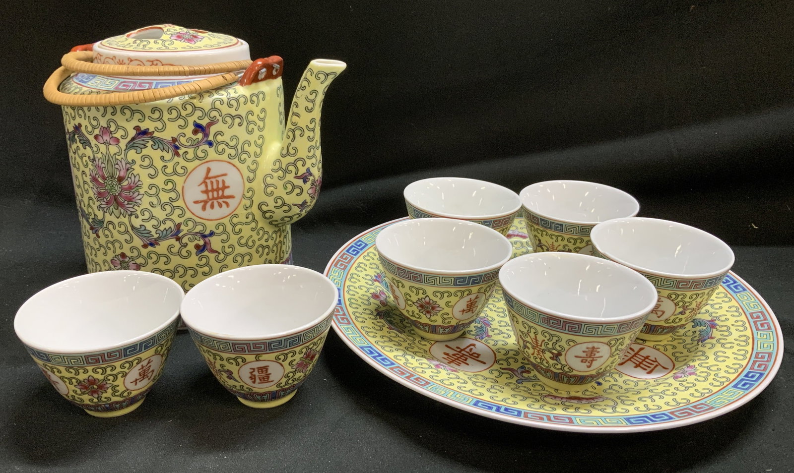 Lot 9 Chinese Mun Shou Longevity Teapot Set: Teapot set is porcelain material & features a colorful floral and foliate scroll pattern. The teapot and platter each feature a red circle with a Chinese character for longevity. Includes, teapot, ser