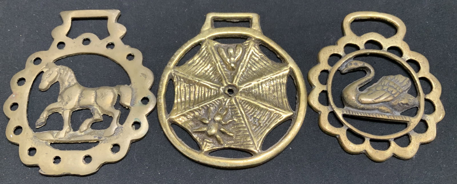 Lot 3 Horse, Web & Swan Horse Brass Medallions: Medallions are horse brass material. Depicts a trotting horse, spider web & swan design. Medallions have a pierced design. Surface wear consistent to age, use & exposure. Measurements: length 3in x wi