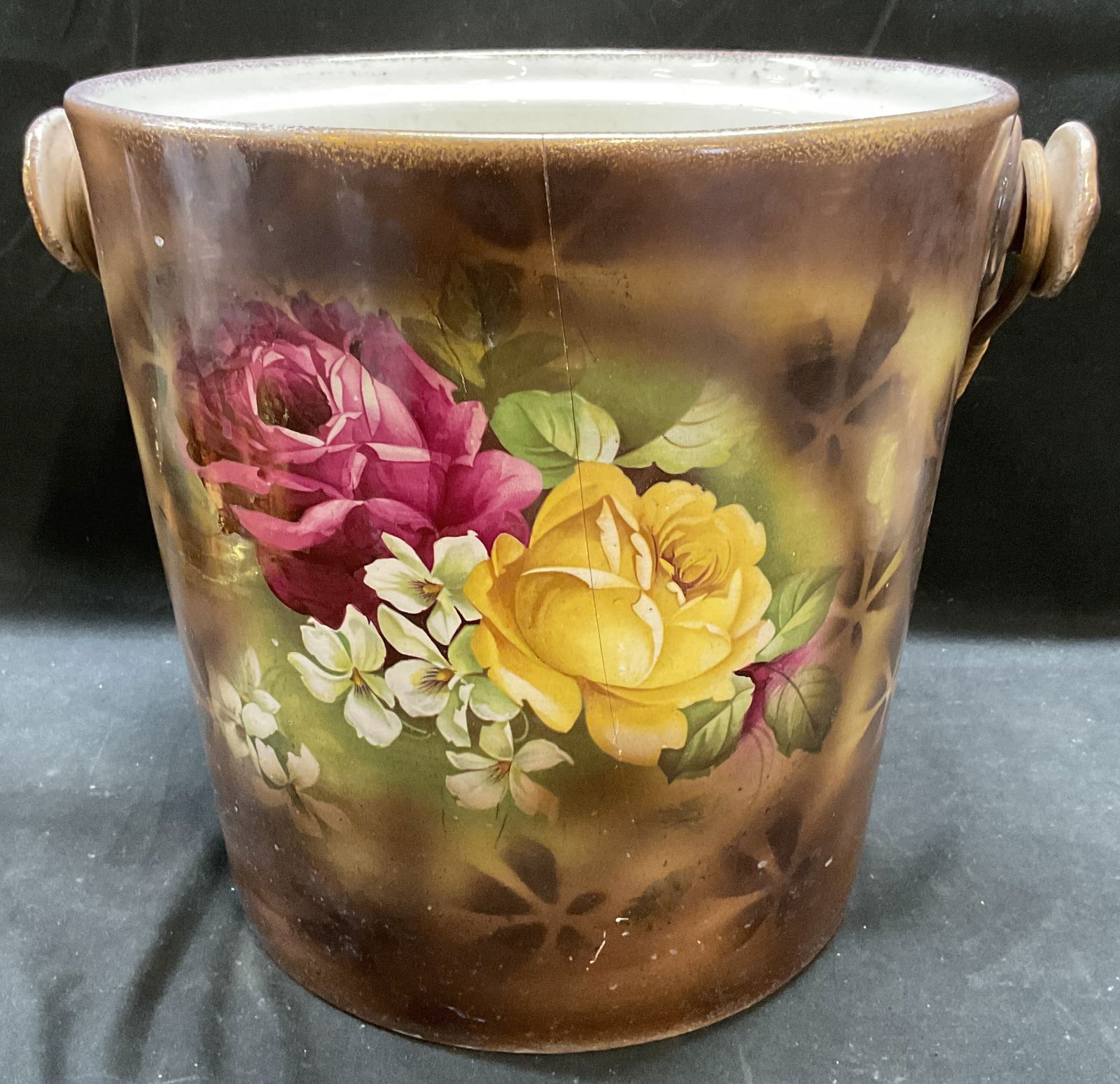 Recessed Lid Porcelain Pot Vessel with Handle: Vintage, possibly antique, porcelain vessel. Recessed concave lid and woven wicker handle. Floral design with gilt decoration. Measures approx 12 x 10 x 10 inches. Surface wear including hairline crac