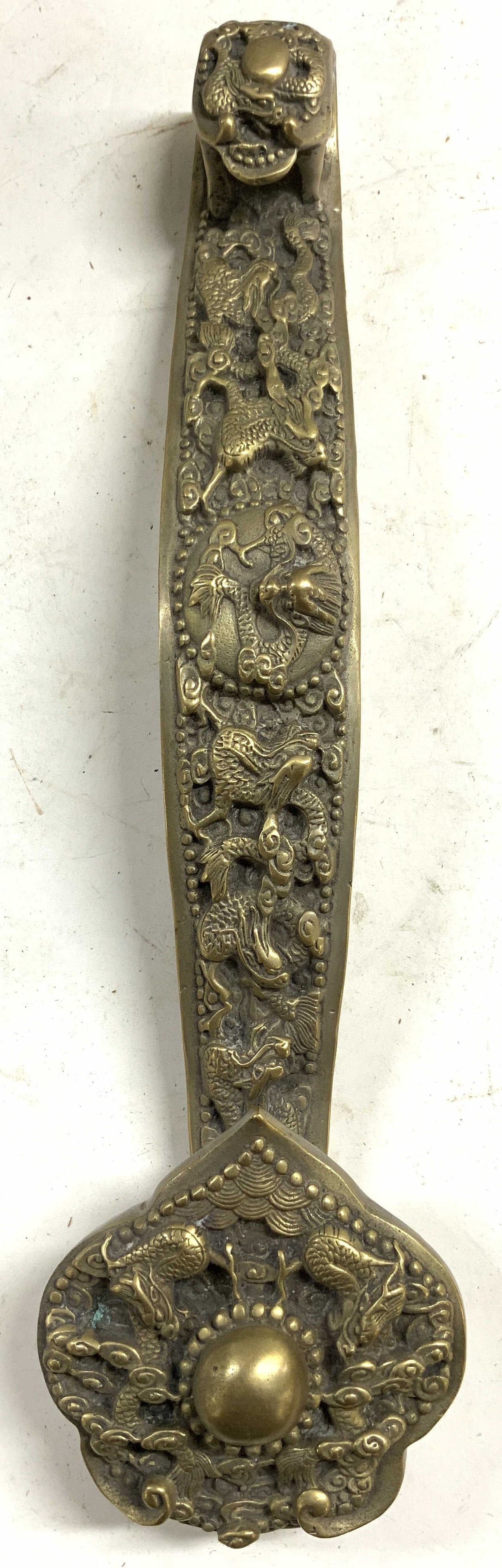 Vintage Asian Brass Door Knocker w Dragon Detail: Door knocker is vintage. Piece is gold toned and brass. Door knocker has intricate dragon relief detail. Sides of piece has relief pattern detail. Door knocker measures approximately 15 inches long 3.