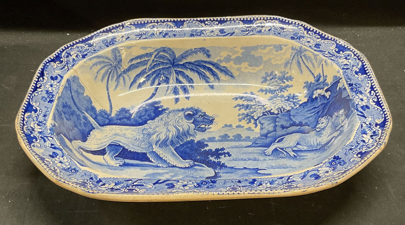 Enoch Wood & Son Lion Transferware Pottery Bowl: Antique Enoch Wood & Son pottery serving bowl. Oval shaped with raised curved edge. Transferware in blue. Anima scenes, Lions and antelopes. Stamped on underside. Made in England. Measures approx 12.5