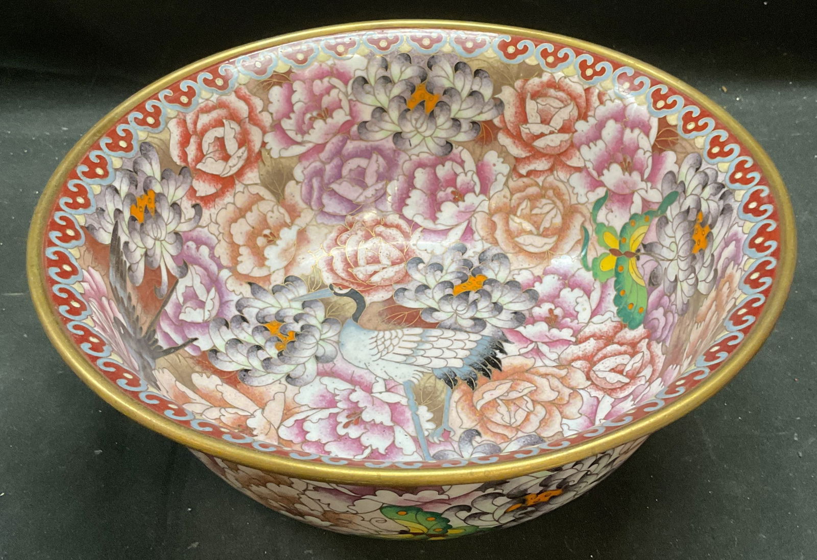 Vintage Cloisonne Enamel Heron Floral Bowl: Vintage cloisonne bowl. Hand painted enamel over brass. Design with heron, butterfly, and flowers in red, purple, green. Measures approx 10 x 4 inches. Bowl has weight. Some scratching. Cloisonne bowl