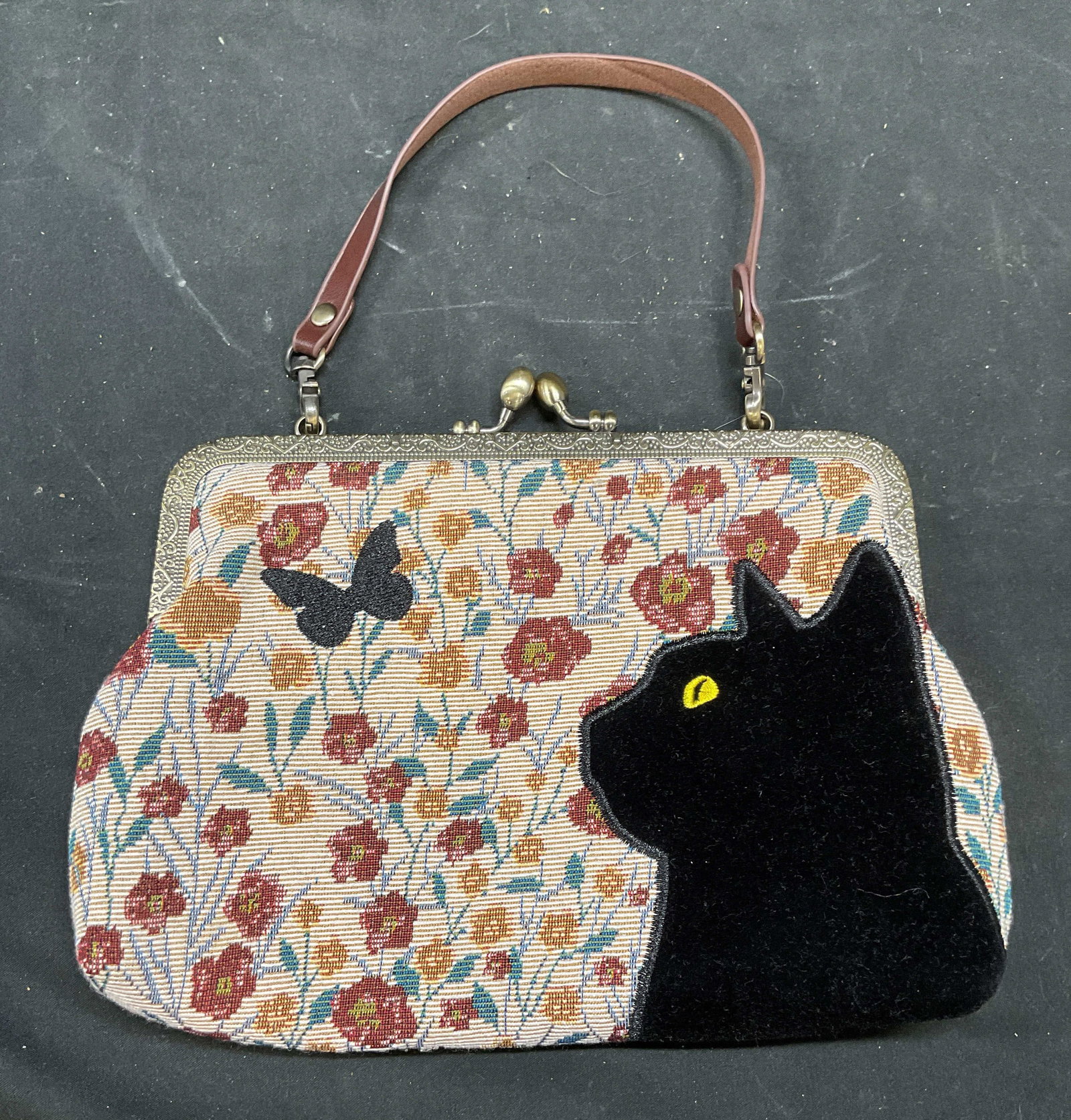 Red & White Floral Tapestry Velvet Cat Handbag: Red and white floral tapestry handbag with black velvet cat and butterfly design. Includes additional chain strap. 2 interior pockets. Measures approx 9 x 6 inches. Some wear consistent with exposure.