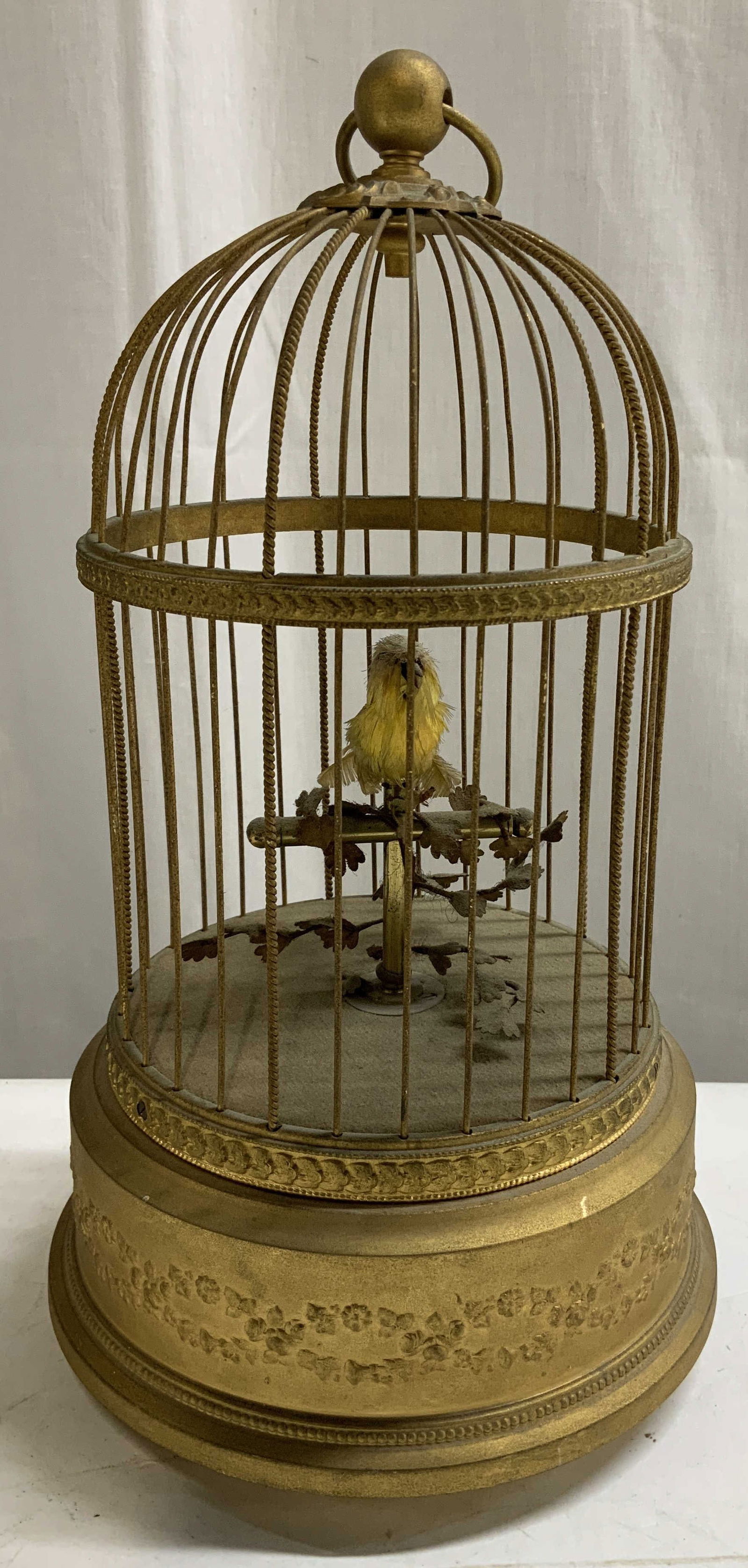 Vntg Gilt Metal Automaton Singing Bird FRANCE: Vintage gilt metal birdcage featuring a yellow bird perched on a branch. Cage has embossed floral detailing. When activated, the yellow bird moves & sings, mimicking lifelike motion. Signed & marked o