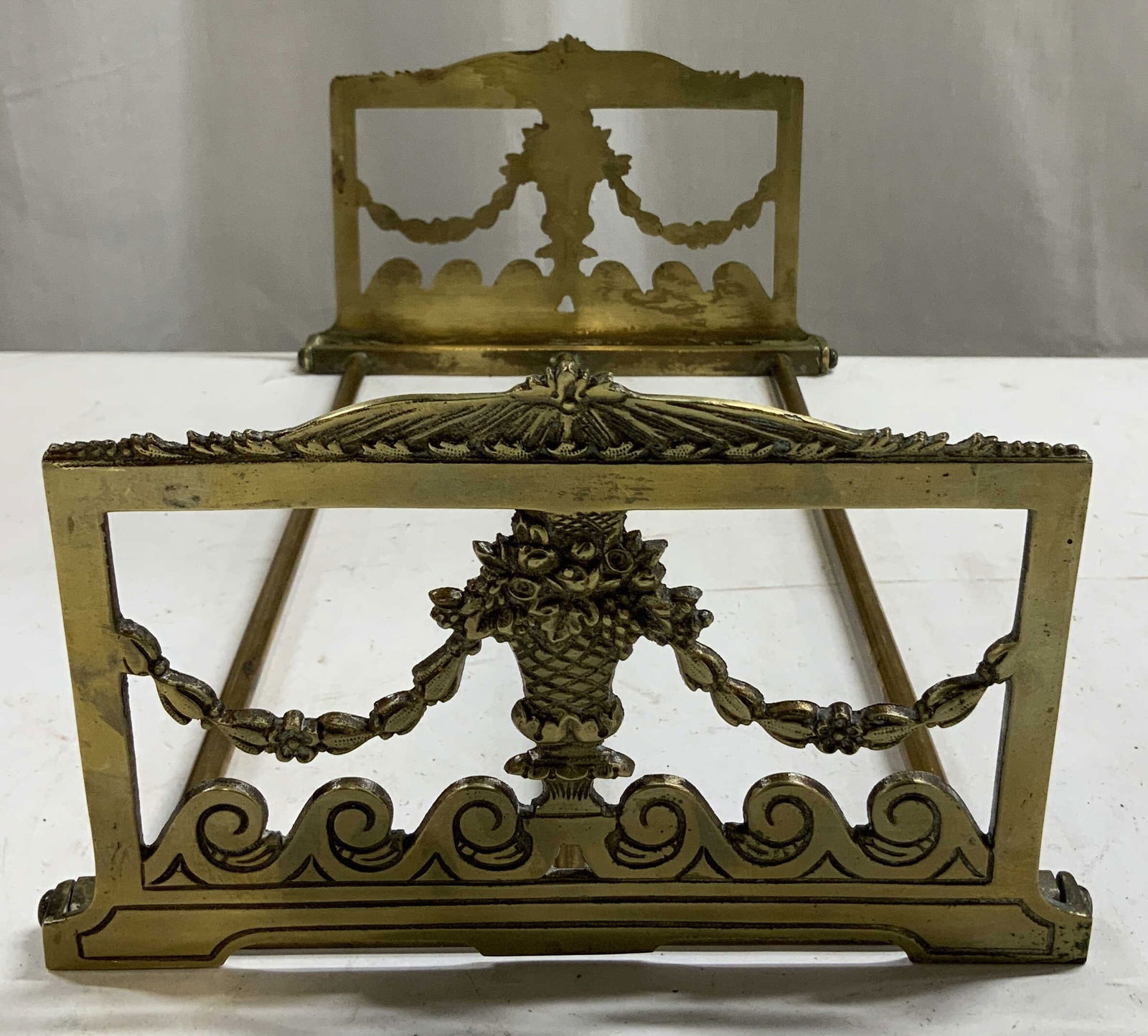 Vntg Ornate Brass Expandable Bookend: Brass bookend features draped floral swags, scroll accents & a central flower medallion. Neoclassical style. Bookend is expendable & folds. No visible signature or markings. Surface wear consistent to