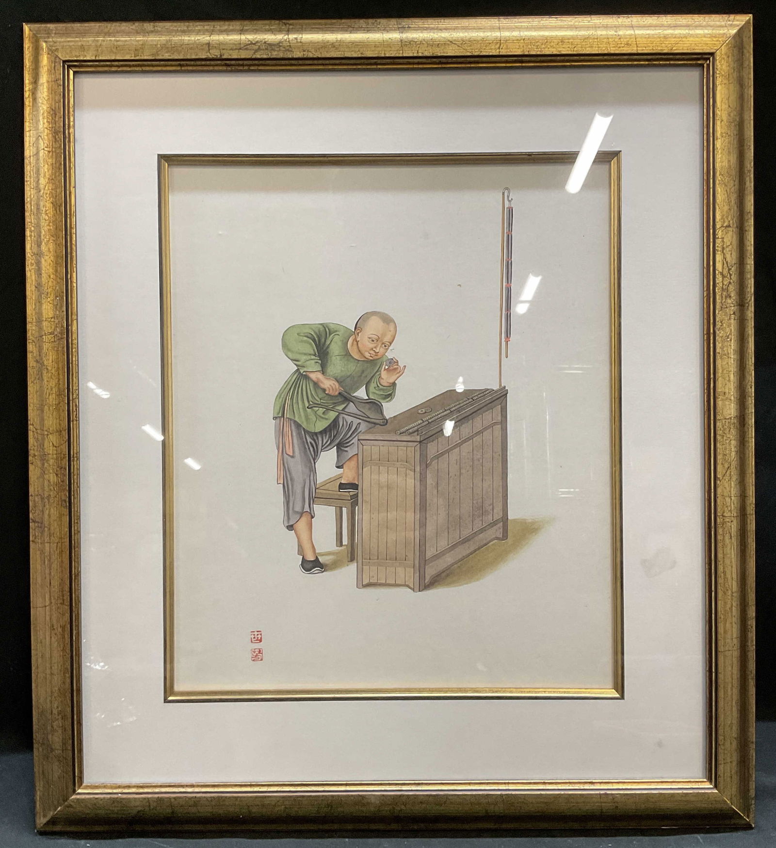 Framed Chinese Man Working Painting: Framed and matted painting on paper. Traditional Chinese scene, man at workbench. Red seal at lower left. Gilt wood frame. Not examined out of frame. Frame measures approx 18 x 15.75 inches. Some wear