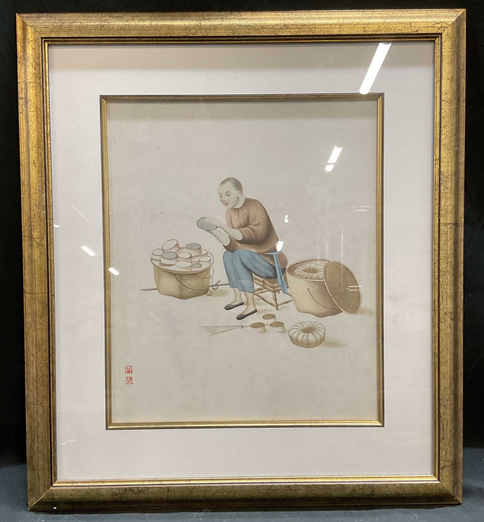 Framed Chinese Tradesman Painting: Framed and matted painting on paper. Traditional Chinese scene, man working his trade. Red seal at lower left. Gilt wood frame. Not examined out of frame. Frame measures approx 18 x 15.75 inches. Some