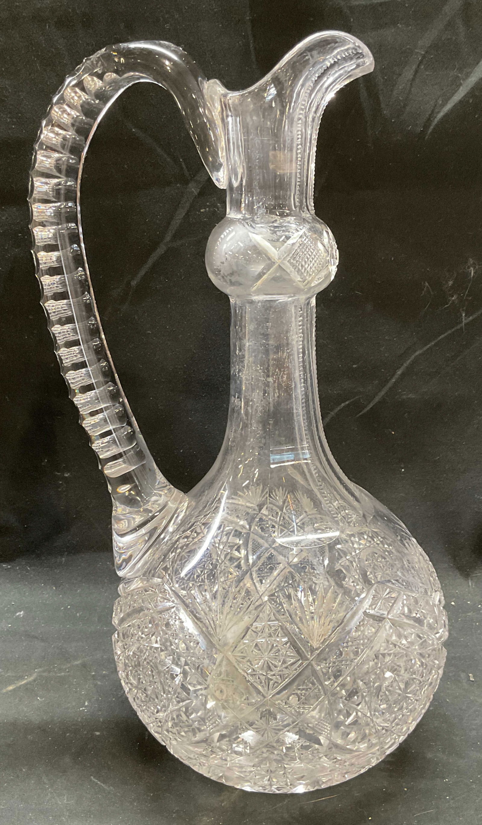 Antique American Brilliant Cut Glass Decanter: Antique American Brilliant Period hand cut glass decanter or ewer. Hob star, fan, and diamond patterns. Notched applied handle. Measures approx 5.5 x 12 inches. Some wear including scratching. America