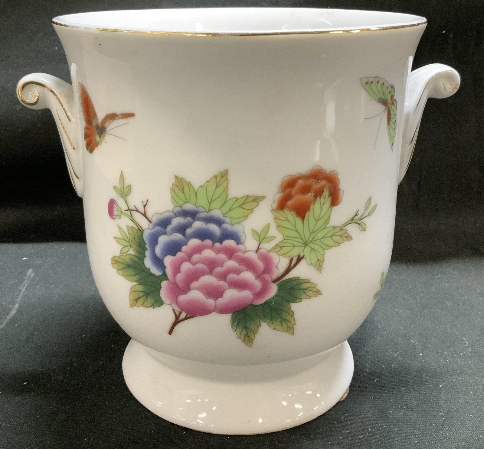 Vintage Floral Porcelain Cache Pot: Cache pot is porcelain material & has hand decorated floral & butterfly motifs. Gold accents on rim & handles. Surface wear consistent to age, use & exposure. Measurements: length 5.5in x width 5.5in 