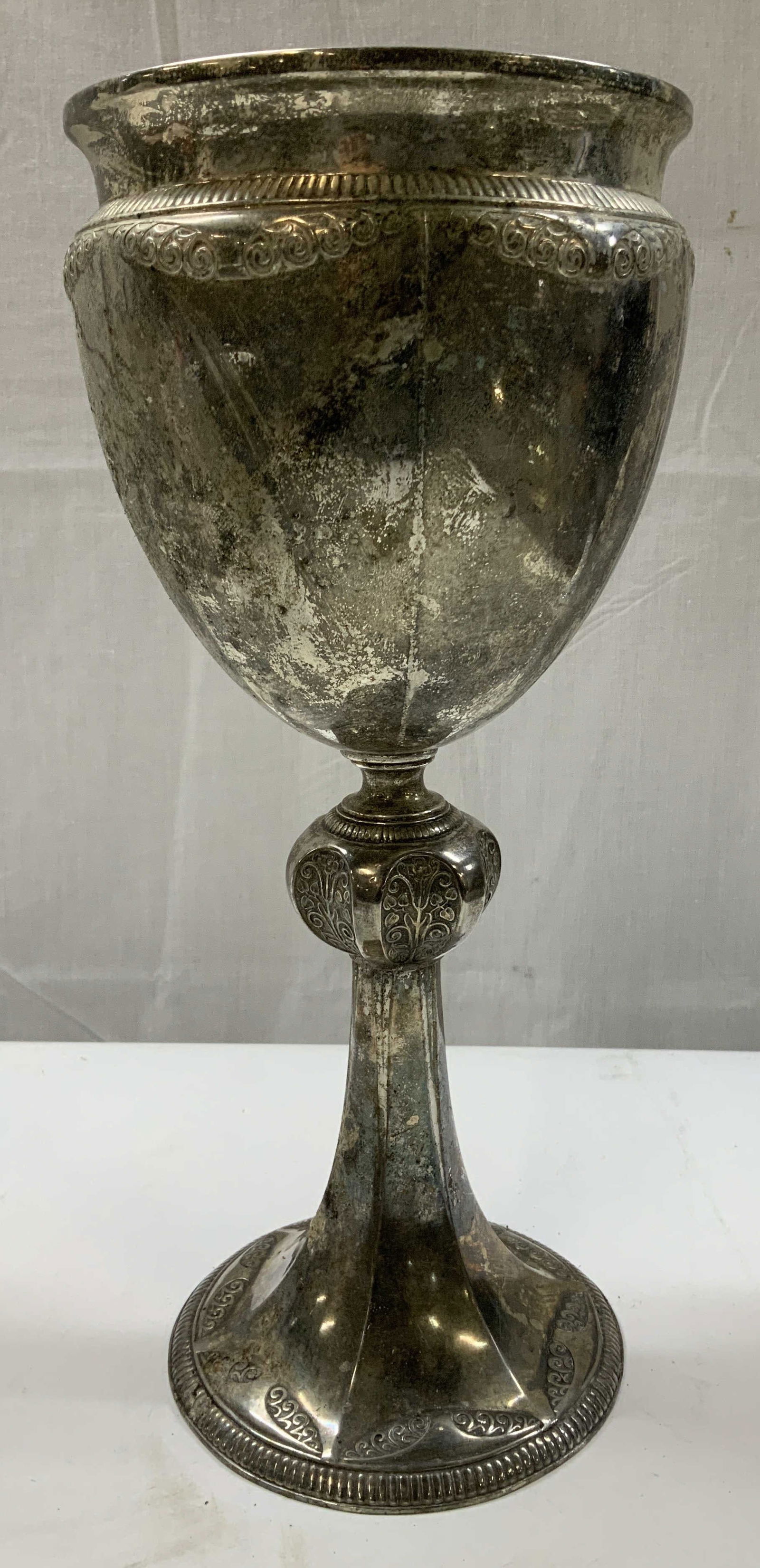 Vntg Silver Plated Ornate Ceremonial Chalice 13in: Vintage chalice featuring a fluted goblet form w detailed scrollwork & ribbed borders along the rim & base. Floral motifs & circular foot. Surface wear consistent to age, use & exposure. Measurements: