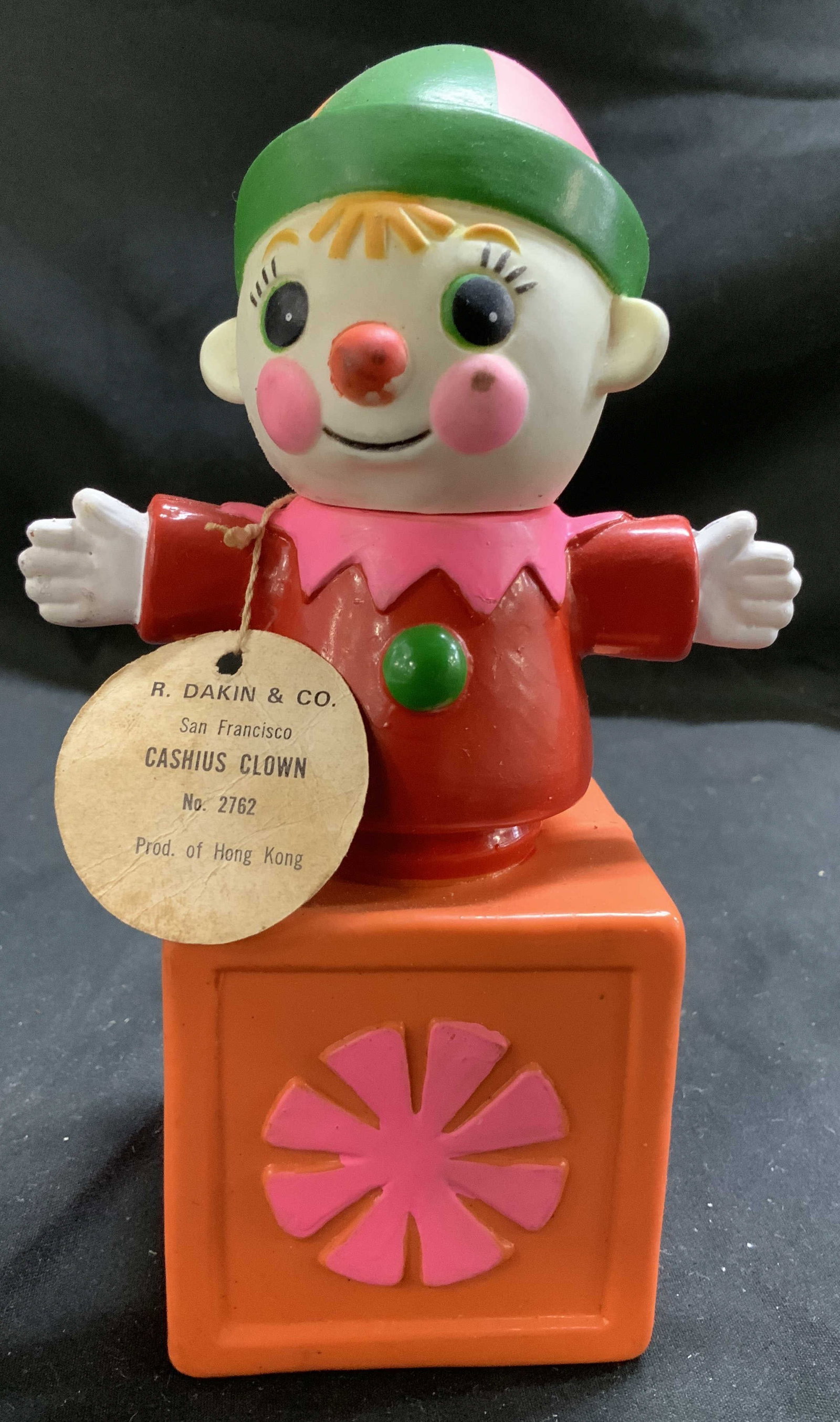 Vntg R.DAKIN&Co. Cashius Clown Coin Bank HONG KONG: Coin bank is plastic & rubber material. Depicts a cashius clown popping out of an orange box. Has a jack-in-the-box style. Comes with original tags. Signed & marked. Reads, R. DAKIN & CO. SAN FRANCISC