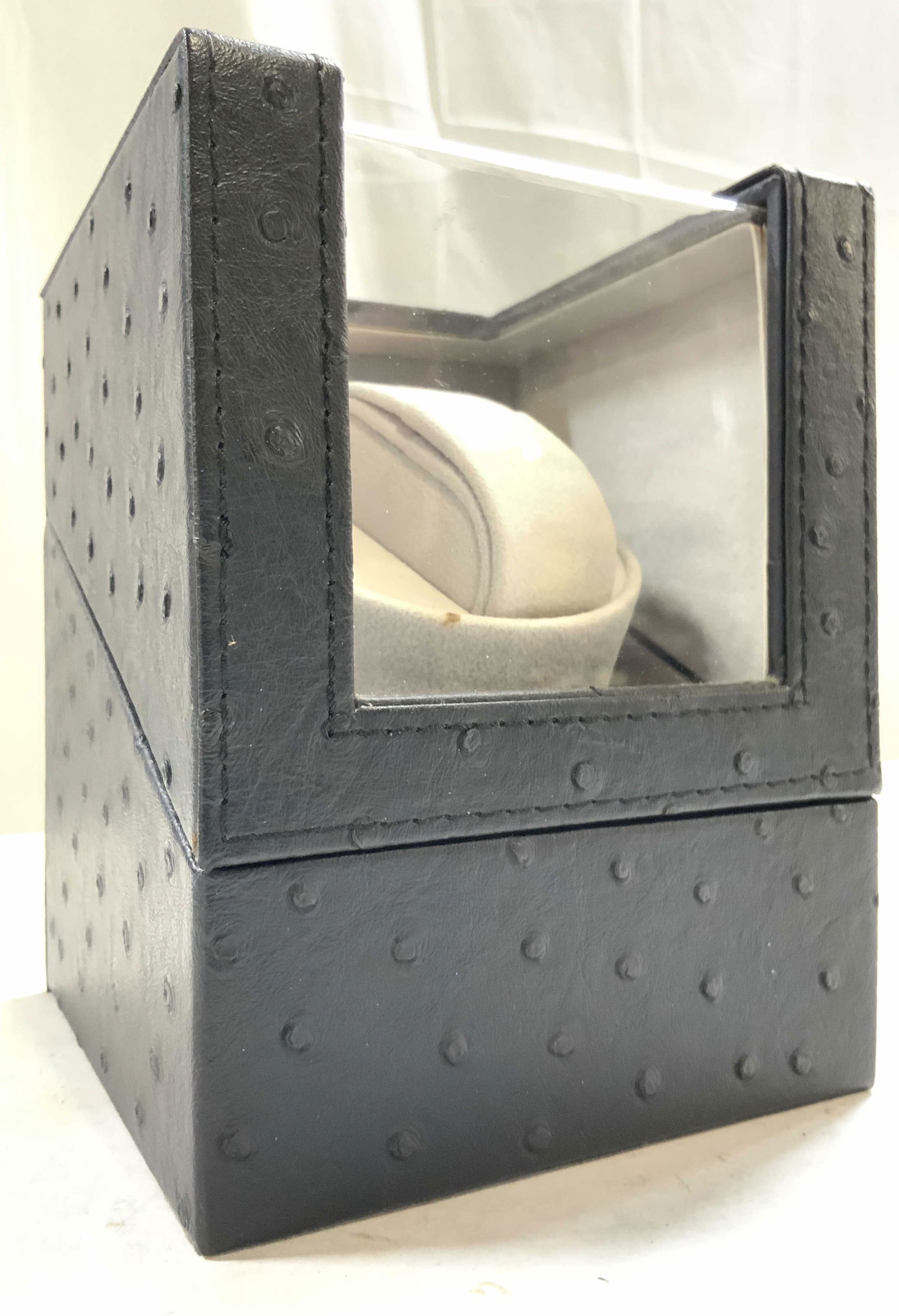 Ostrich Leather Watch Box W Lid Black: Watch box is black toned appears to be lined in Ostrich leather. Interior is light slate toned. Box includes lid. Piece measures approximately 6.25 inches tall 4.75 inches wide 5 inches deep. Watch bo