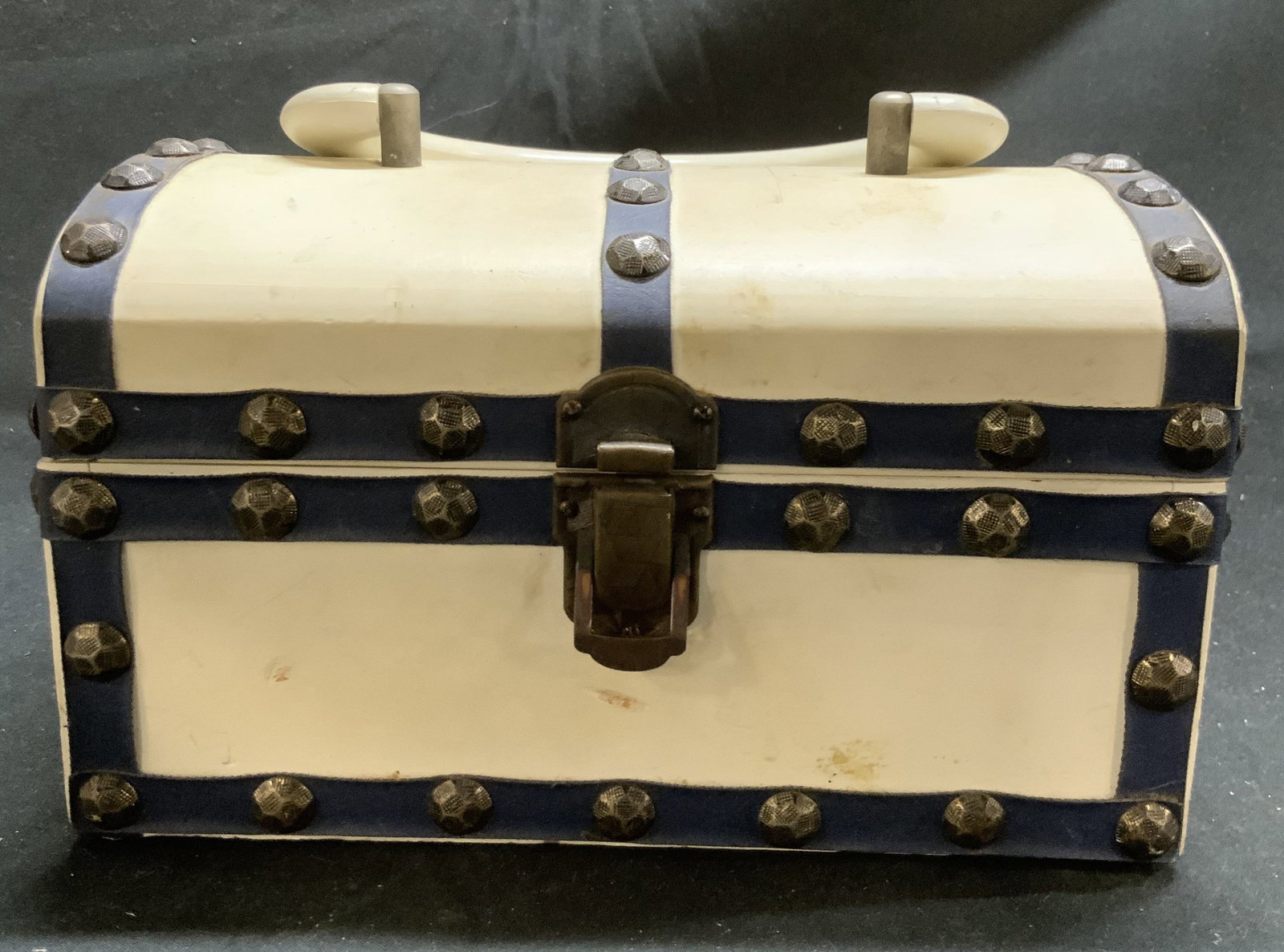 ROYAL LONDON Wood Purse Bx W Nailhead Detail: Tag on underside reads ROYAL LONDON LTD. Box has treasure chest form with handle at top. Piece is white with navy toned accents and nailhead detail. Interior is lined with navy toned velvet. Piece mea
