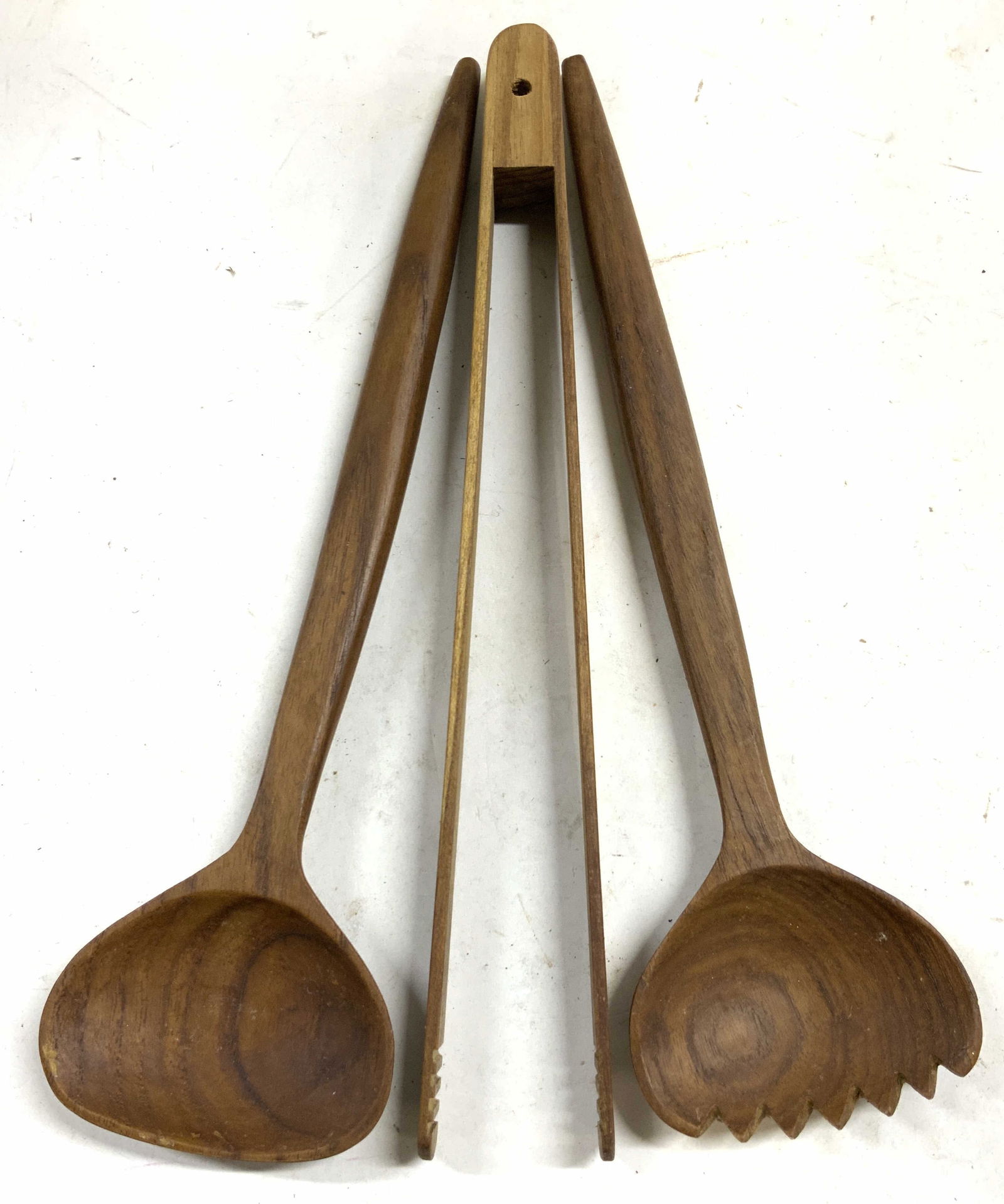 Set 3 Teakwood Salad Serving Utensils: Lot includes 1 salad serving spoon, 1 pair of tongs, and 1 salad serving fork. Each piece is brown toned & appears to be teakwood. Tongs measure approximately 12 inches long 2 inches wide. Salad servi