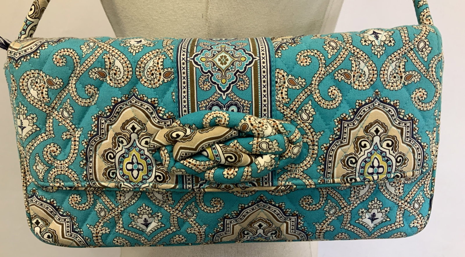 Vera Bradley Knot Just a Clutch Shoulder Bag: Quilted shoulder bag featuring a paisley-like pattern in turquoise, tan, brown, and cream colors. Bag features a knot detail on the front flap and a detachable strap. Signed & marked. Reads, VERA BRAD